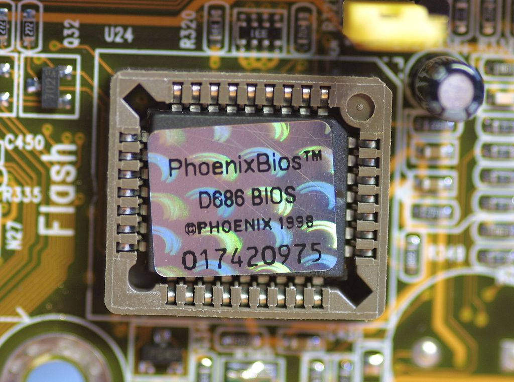 科技動圖 桌布 壁紙 — 綠色電路板上Phoenix BIOS晶片的特寫，可見焊點和組件標籤。