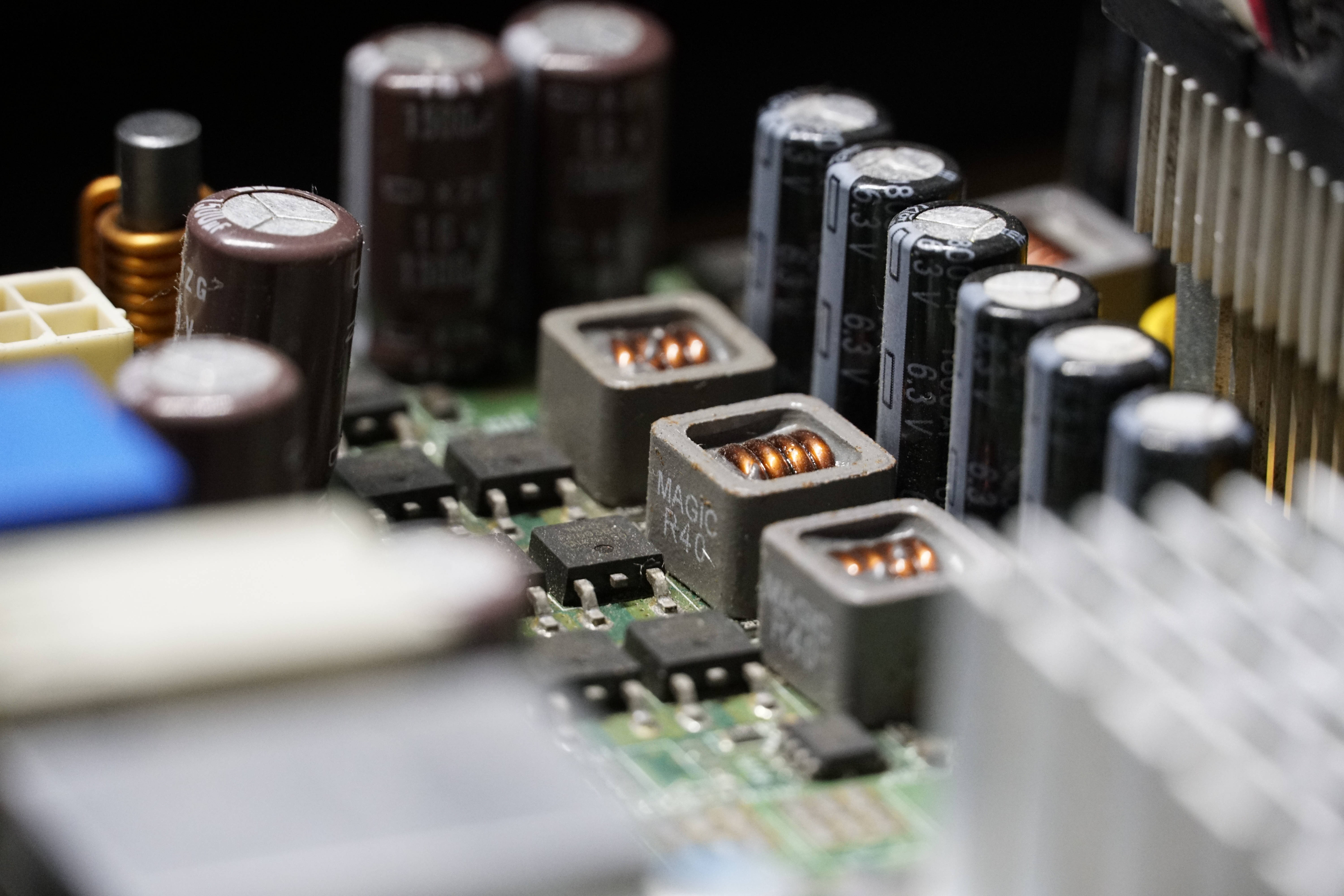Motherboard 桌布 壁紙 — 綠色電路板上電容器和電感器等電子元件的特寫微距拍攝，景深較淺。