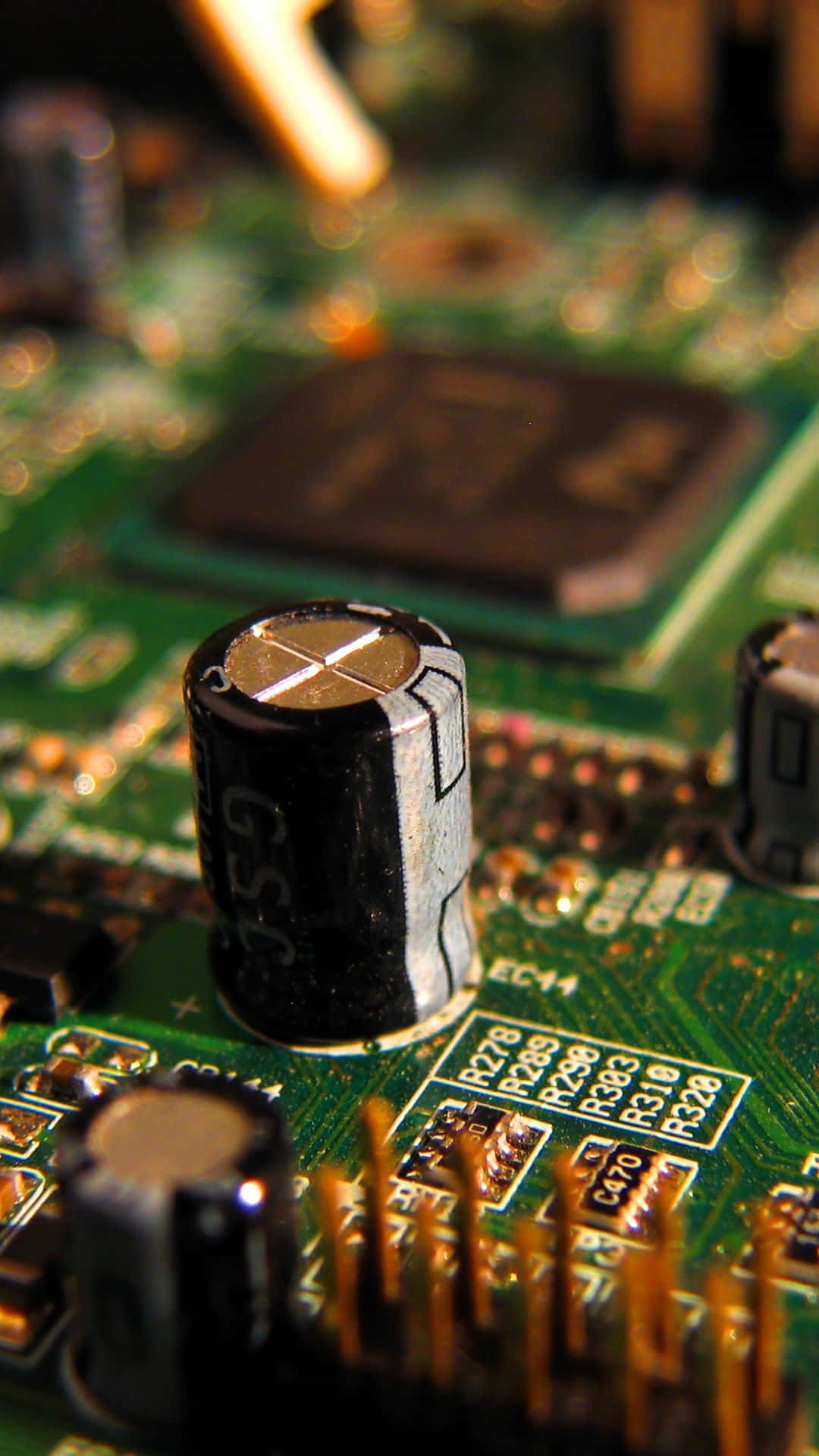 Electronic Components 桌布 壁紙 — 綠色電路板的特寫微距照片，黑色圓柱形電容器在模糊的電子元件背景下清晰對焦。