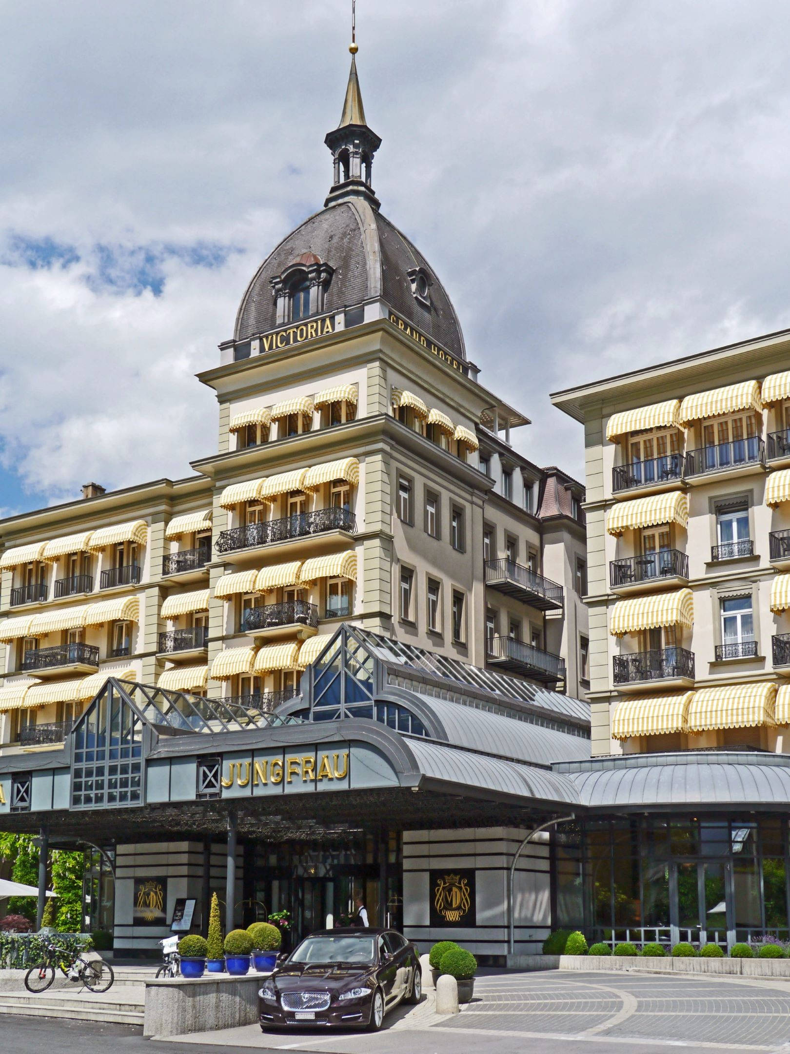 Switzerland 桌布 壁紙 — 維多利亞大酒店（Grand Victoria Grand Hotel Jungfrau）在陰天天空下設有黃色遮陽篷和圓頂。