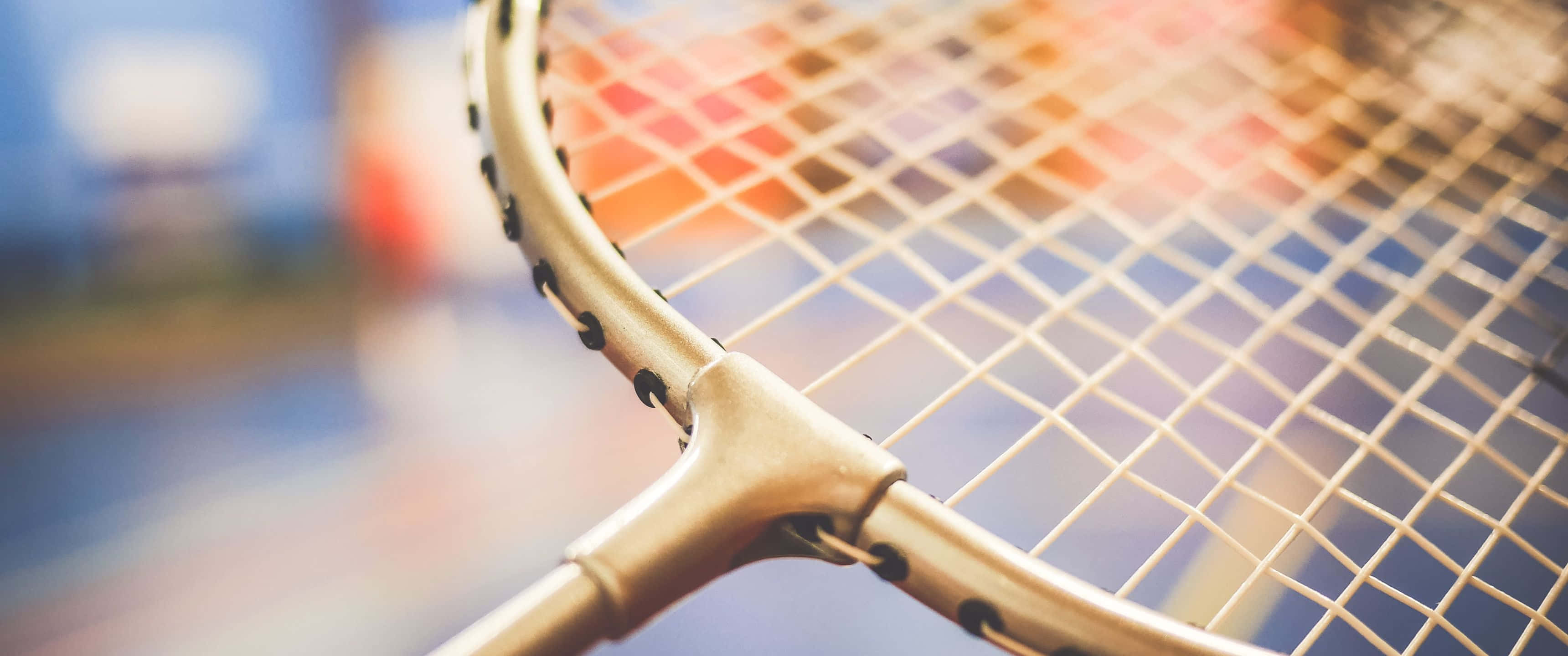 3440x1440p Badminton 桌布 壁紙 — 網球拍頭和線的近距離特寫，溫暖的陽光穿過網格。