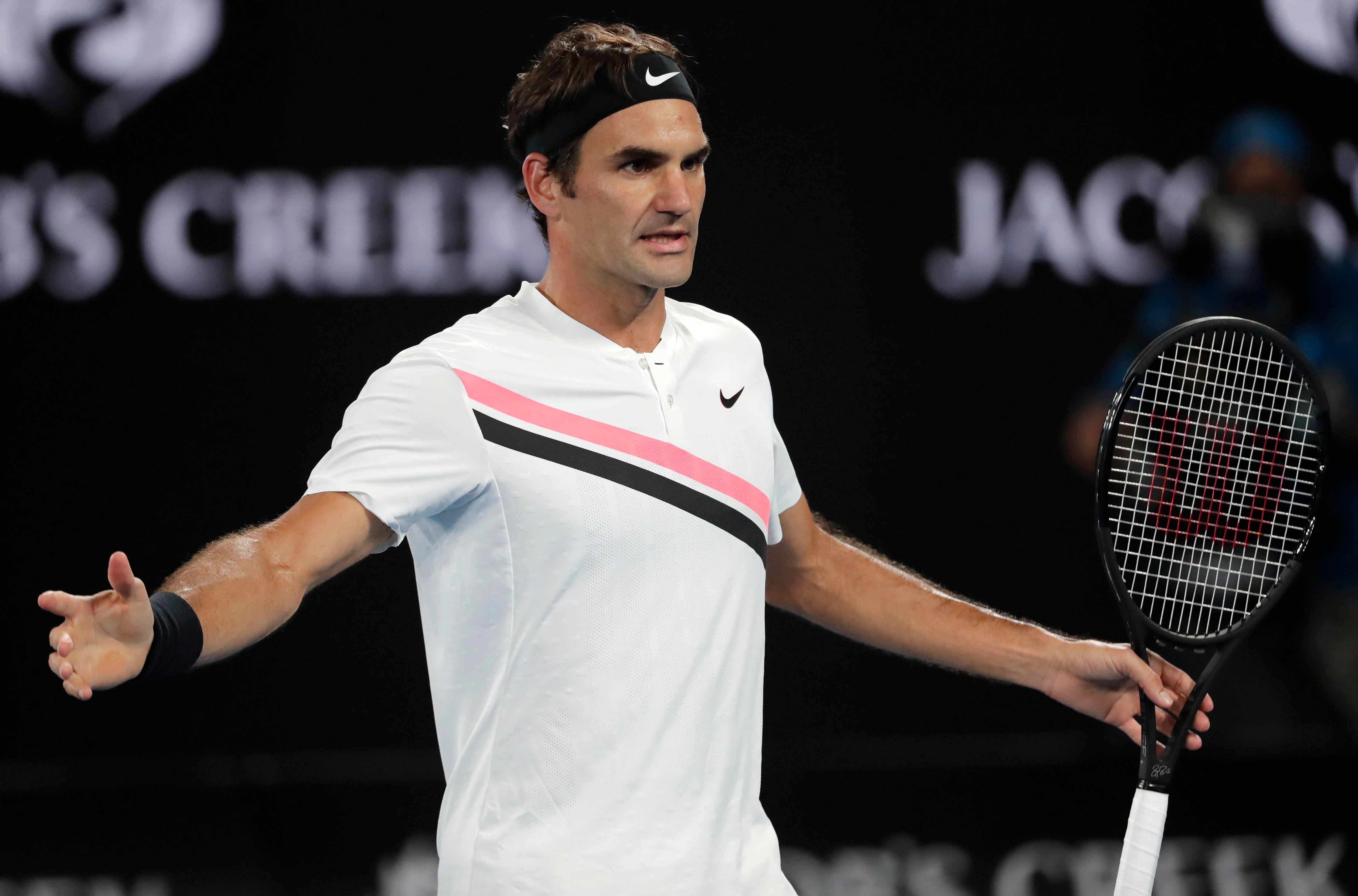 roger 桌布 壁紙 — 網球選手 Roger Federer 在明亮的體育場燈光下張開雙臂握著球拍做手勢。