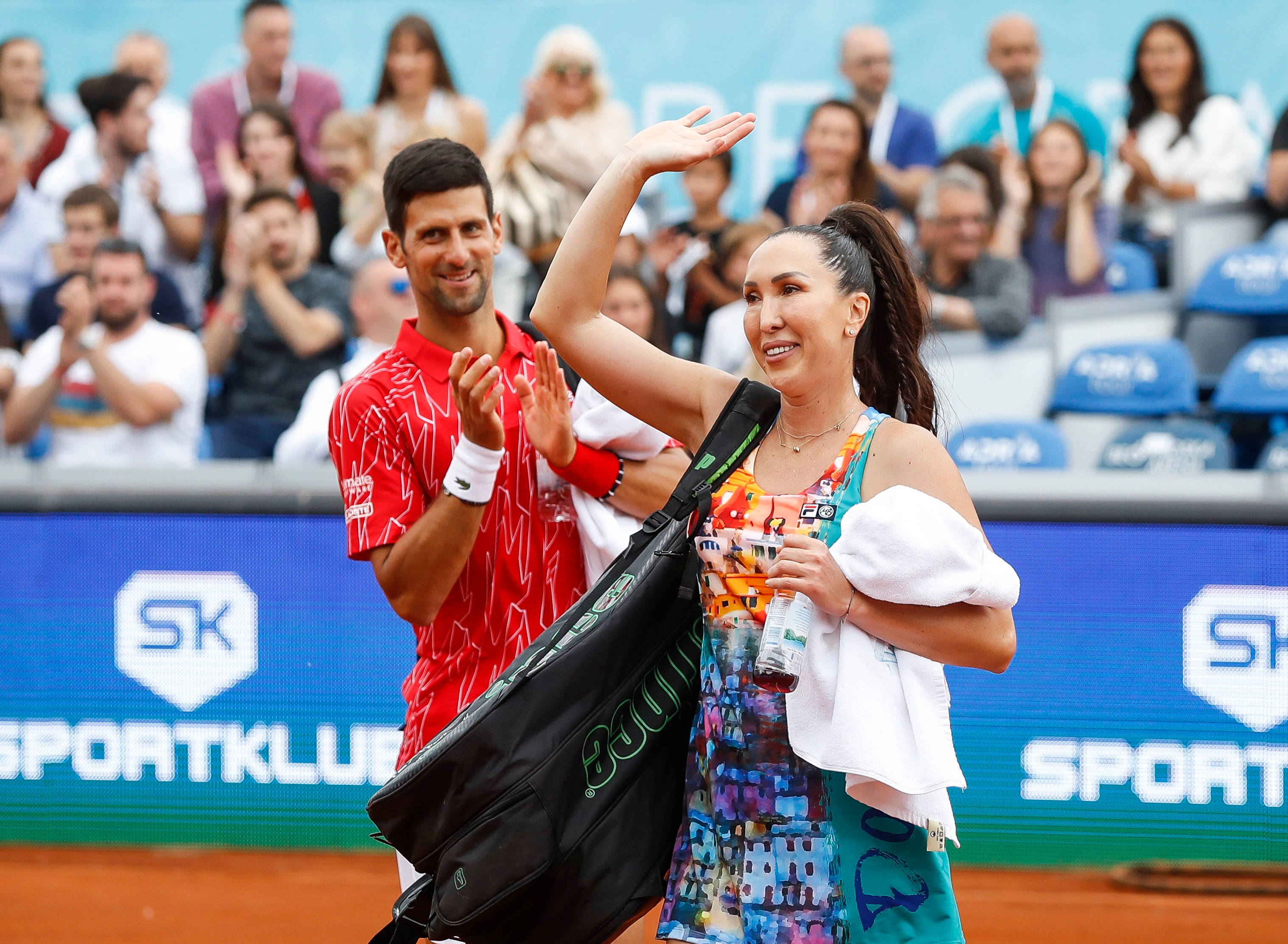 Tennis 桌布 壁紙 — 網球選手在明亮的日光下向紅土球場上歡呼的人群揮手。