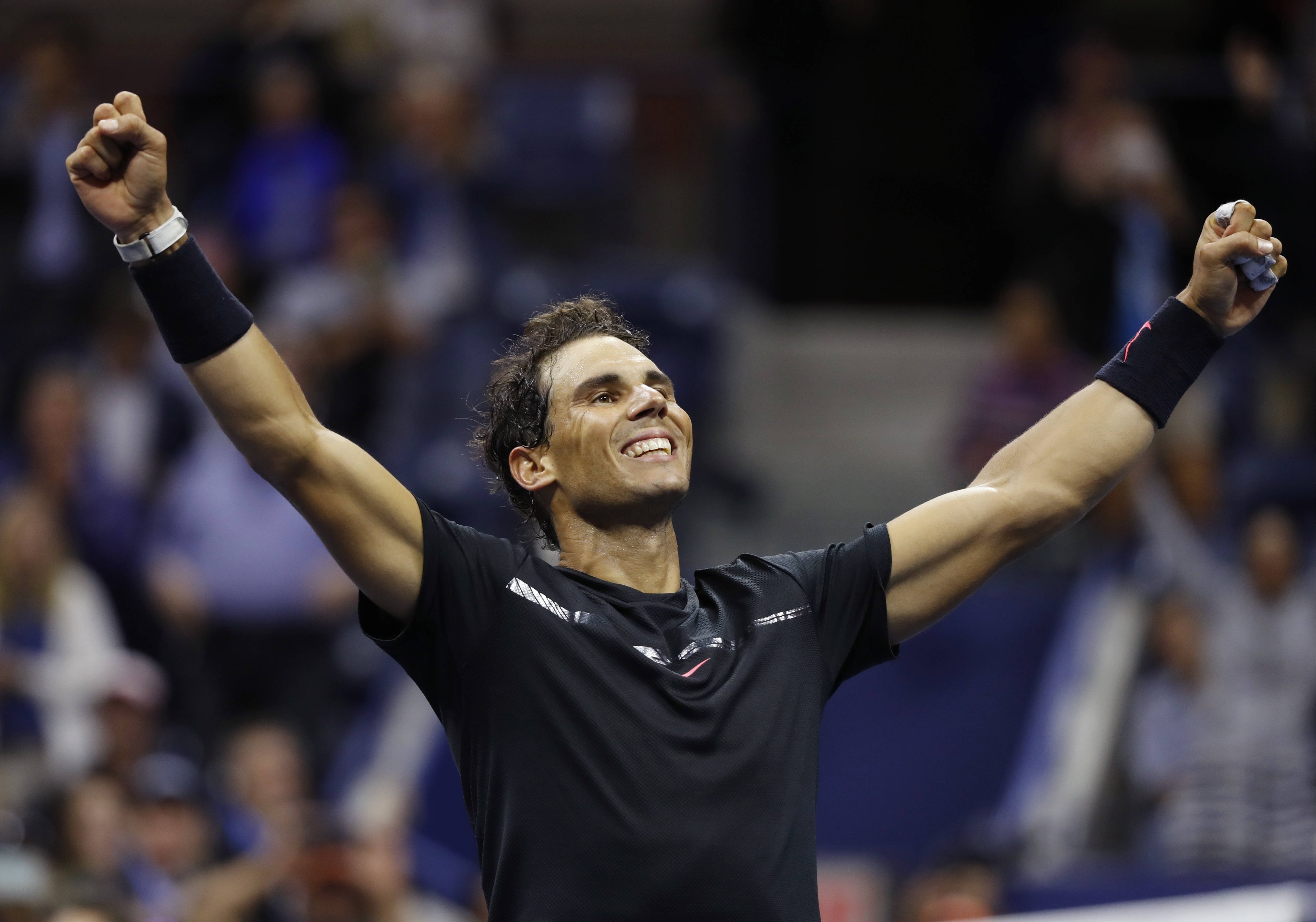 Rafael 桌布 壁紙 — 網球選手拉斐·納達爾在明亮的體育場燈光下比賽時，勝利地高舉雙拳，露出燦爛的笑容。