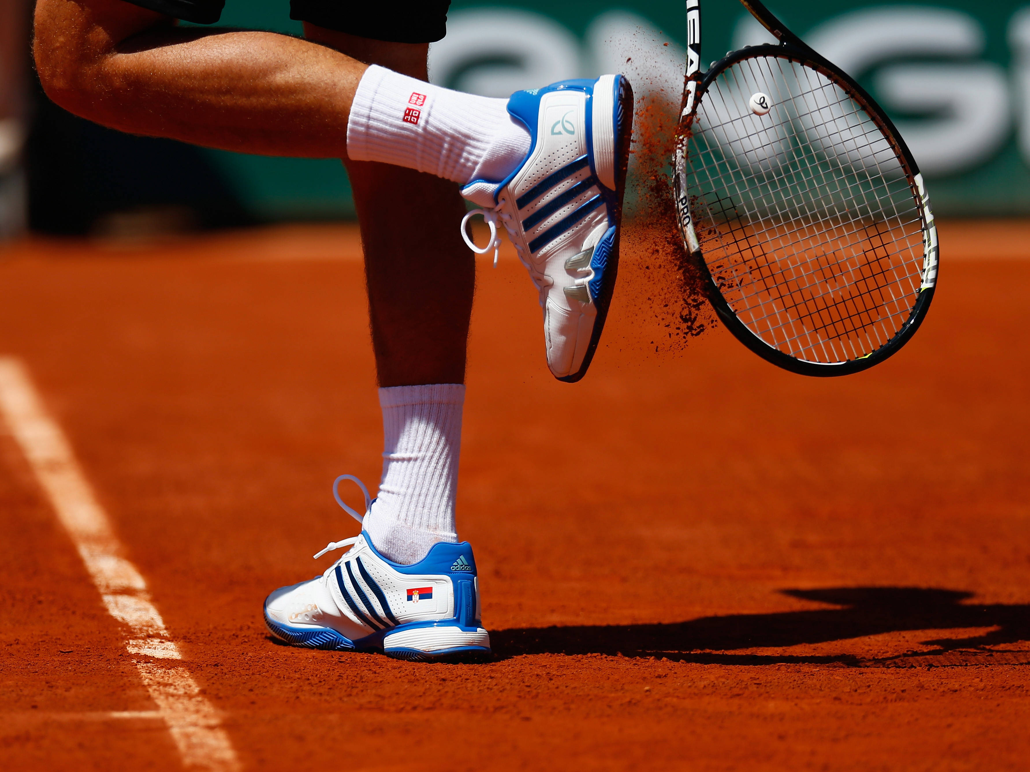 Tennis 桌布 壁紙 — 網球選手的腳在陽光明媚的紅土球場上揮拍時踢起紅色泥塵。