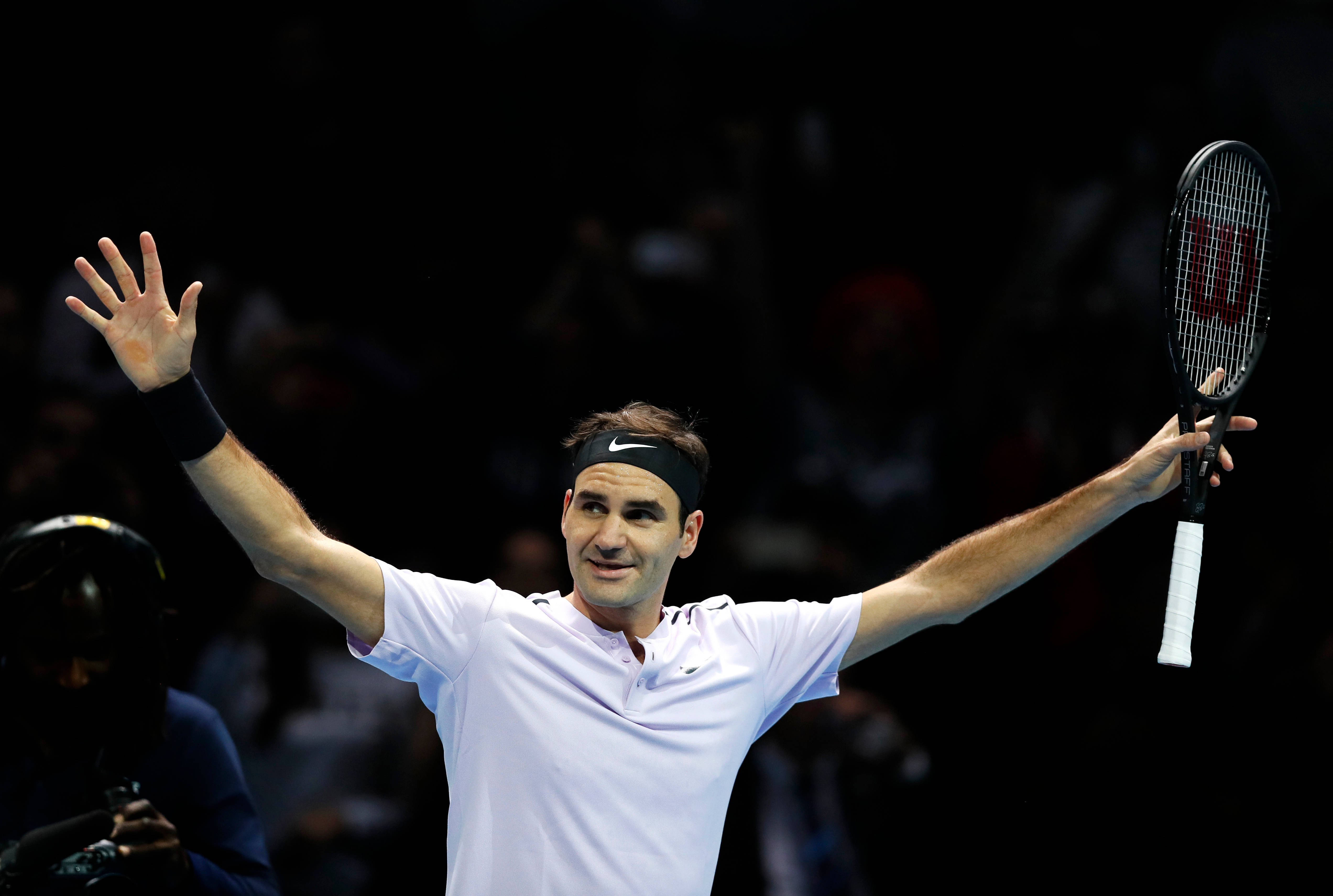 roger 桌布 壁紙 — 網球選手羅傑·費德勒在場館燈光下高舉手臂慶祝勝利，手持球拍。