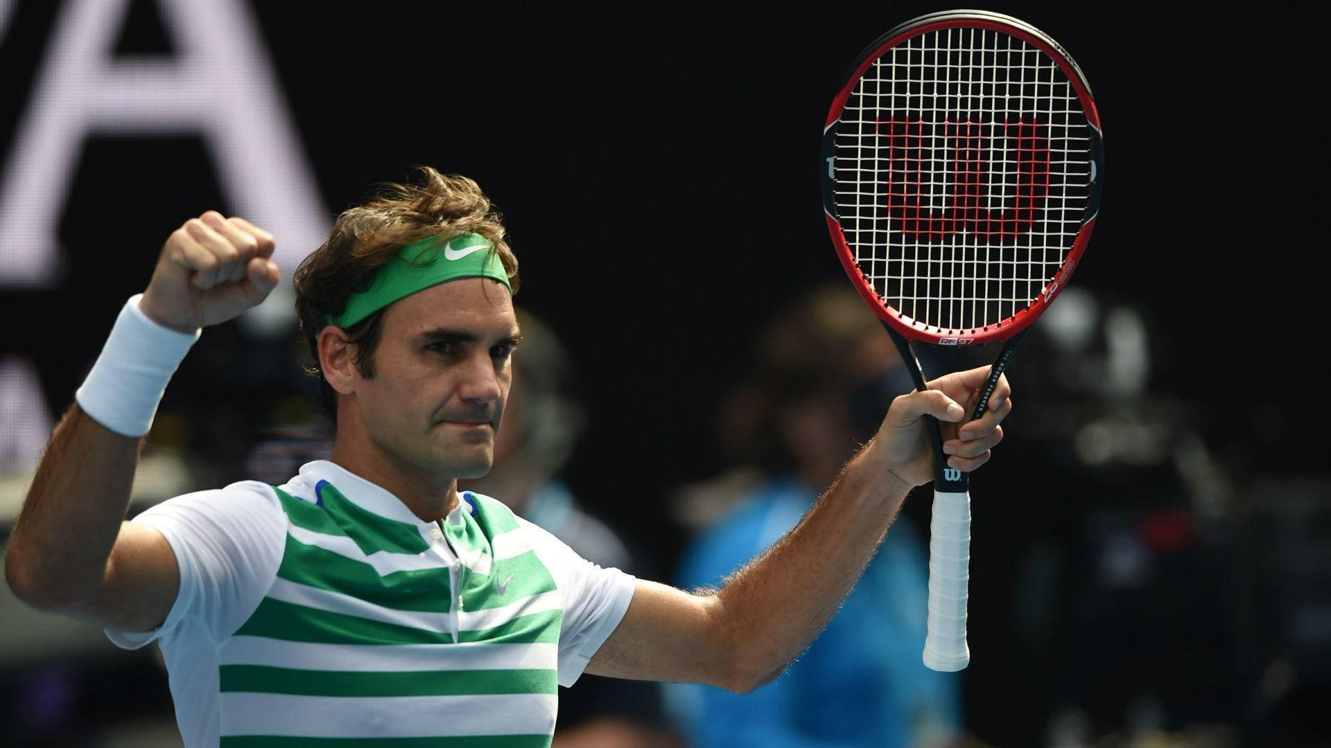 roger 桌布 壁紙 — 網球選手羅傑·費德勒在明亮的體育場燈光下高舉拳頭和球拍慶祝勝利。