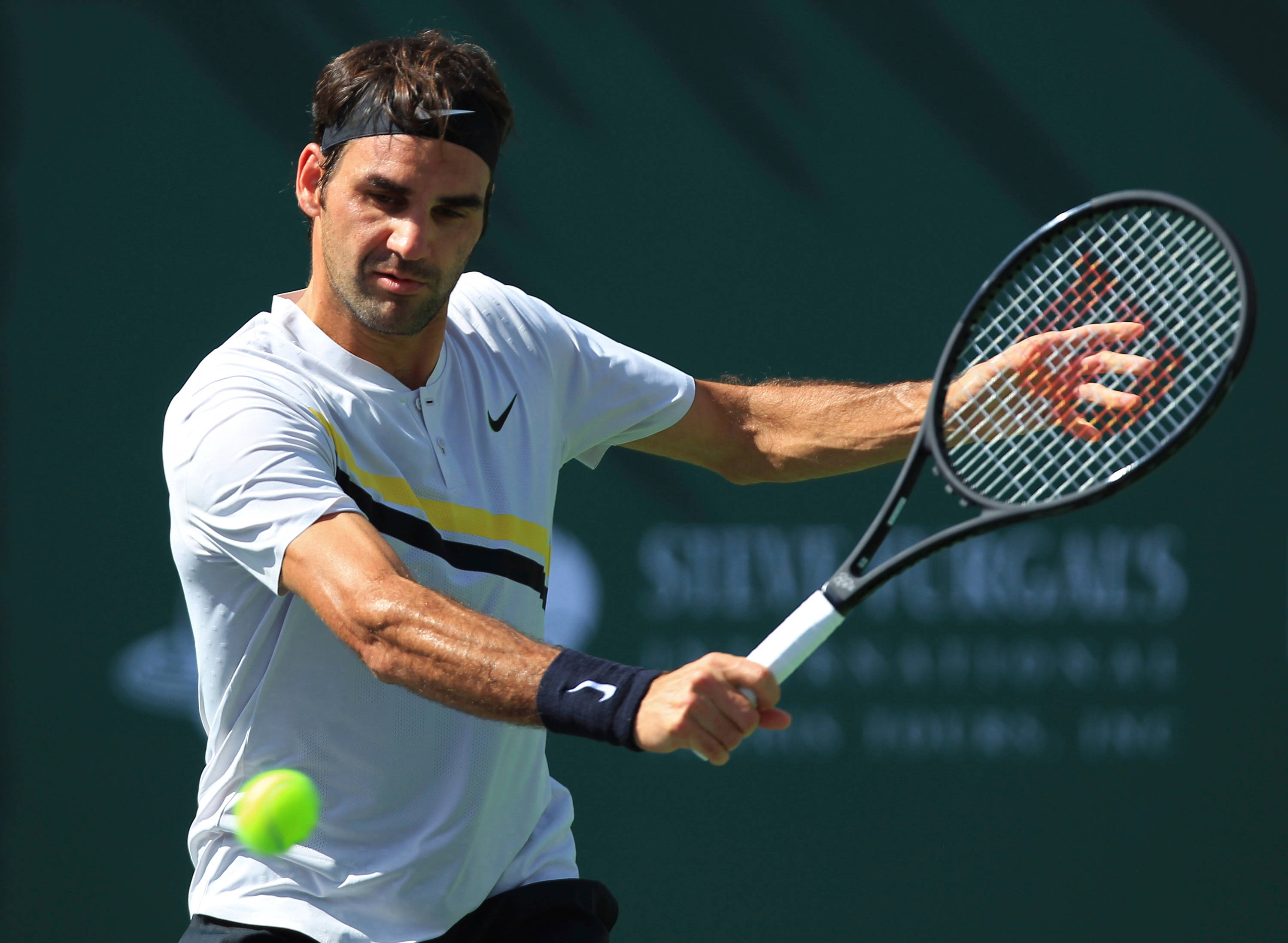 roger 桌布 壁紙 — 網球選手羅傑·費德勒在陽光普照的球場上比賽時，揮動球拍擊向一顆亮綠色的球。