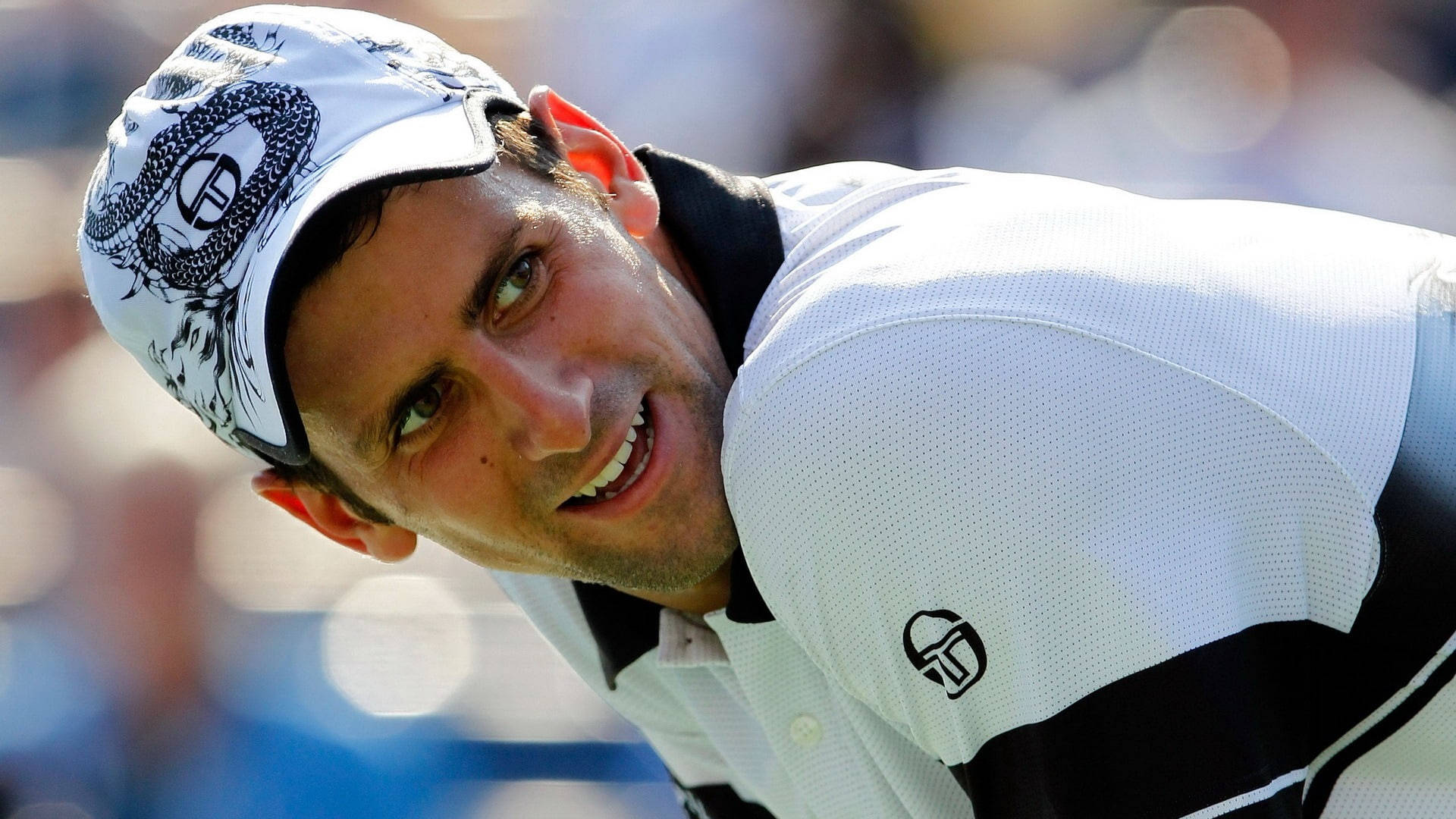 Novak 桌布 壁紙 — 網球選手諾瓦克·喬科維奇戴著白色帽子與Polo衫，向前傾，露出燦爛笑容。