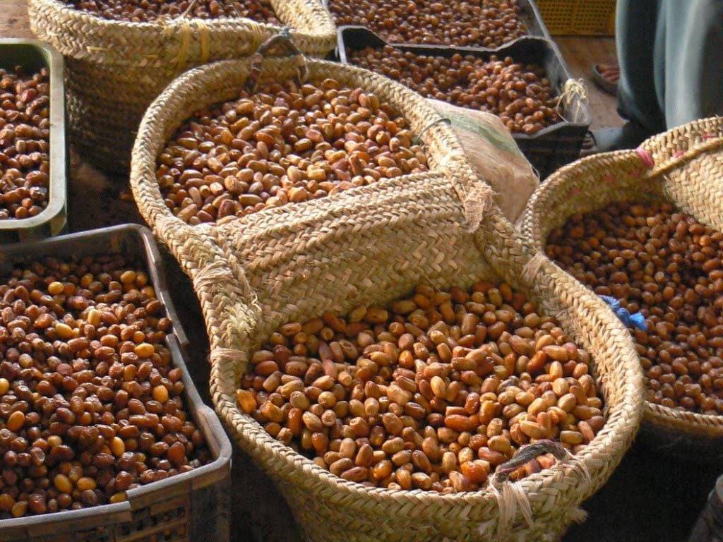 basket 桌布 壁紙 — 編織籃子裝滿金黃色烤花生，在熱鬧的戶外市場攤位上。