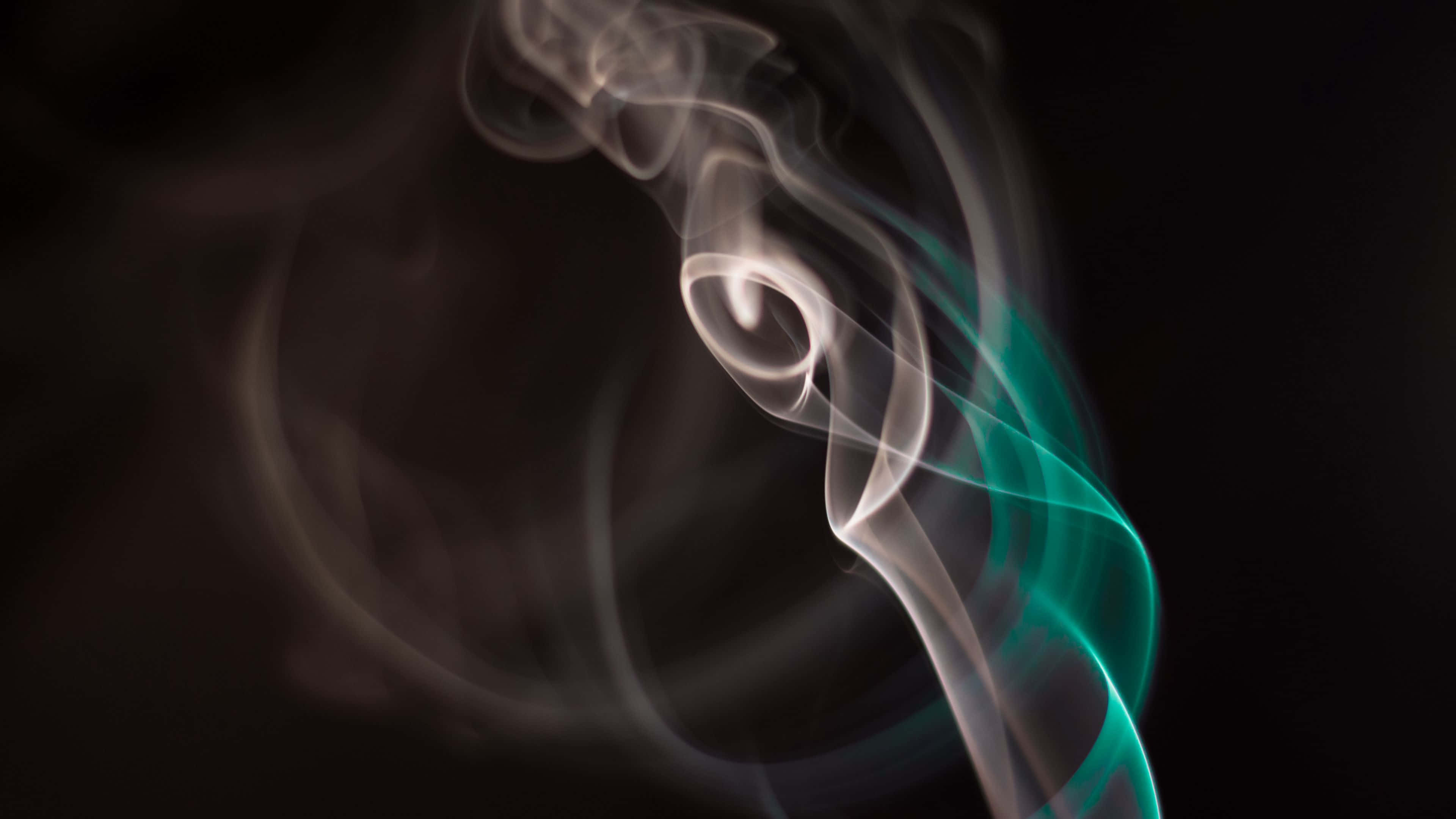 Swirl 桌布 壁紙 — 縹緲的煙霧在黑暗背景下優雅地盤旋，充滿活力的青綠色光芒照亮了其半透明的形態。