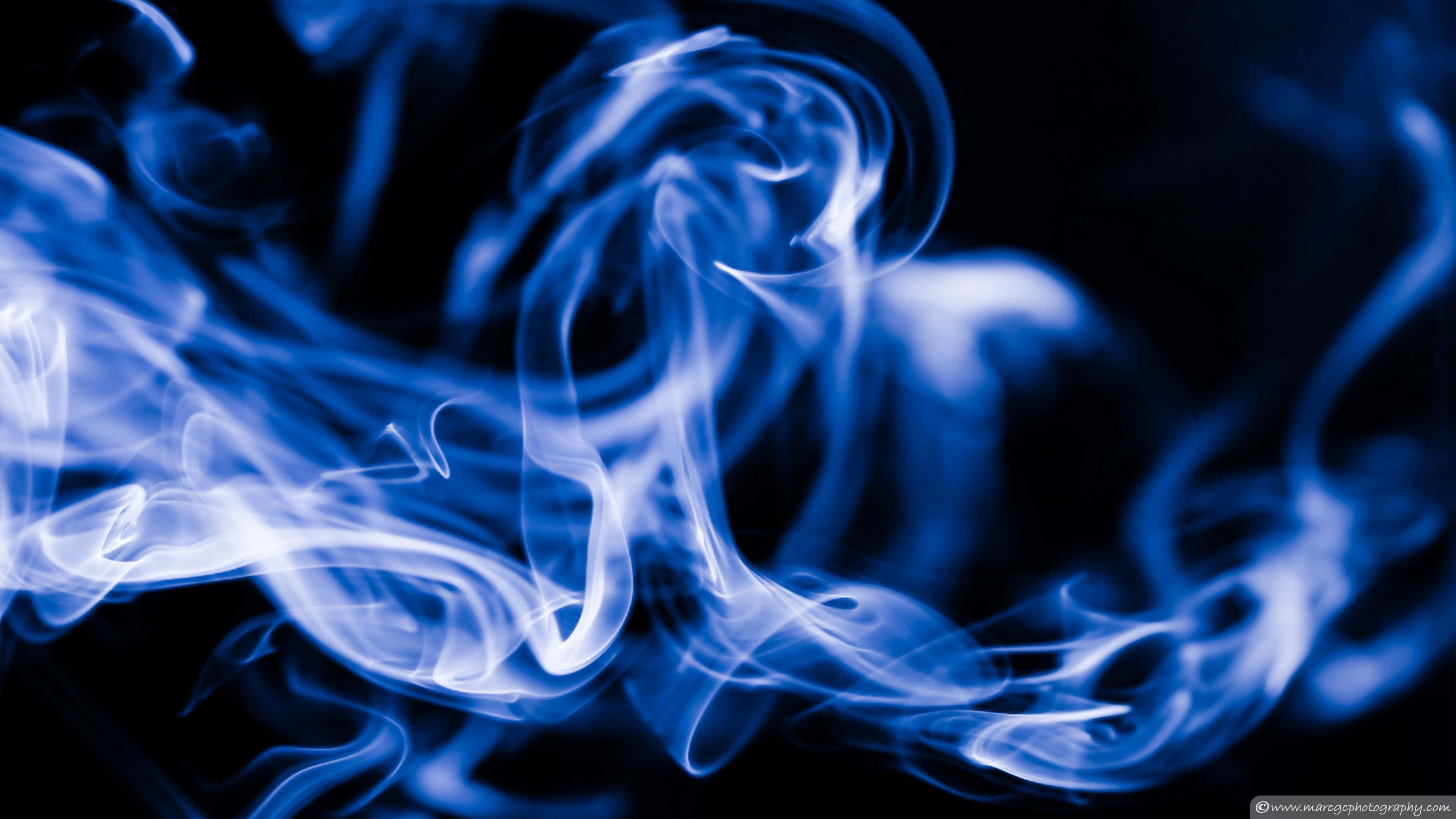 Smoke Blue 桌布 壁紙 — 縹緲的藍色煙霧在深黑色背景上優雅地旋轉，營造出迷人的抽象動感。