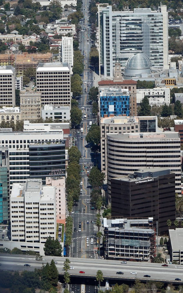 手機 桌布 壁紙 — 繁忙城市景觀的鳥瞰圖，高樓大廈、寬闊街道和汽車在明亮的日光下沿高速公路行駛。