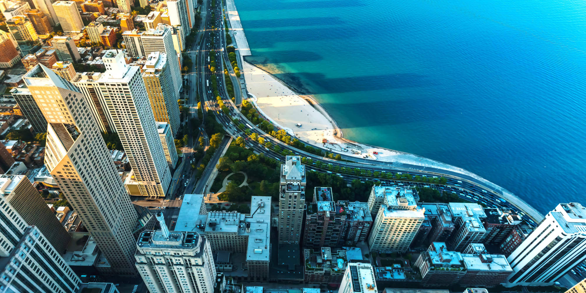 Skyscraper 桌布 壁紙 — 繁忙城市景觀的鳥瞰圖，高聳的摩天大樓擁抱著充滿活力的藍色湖岸線。