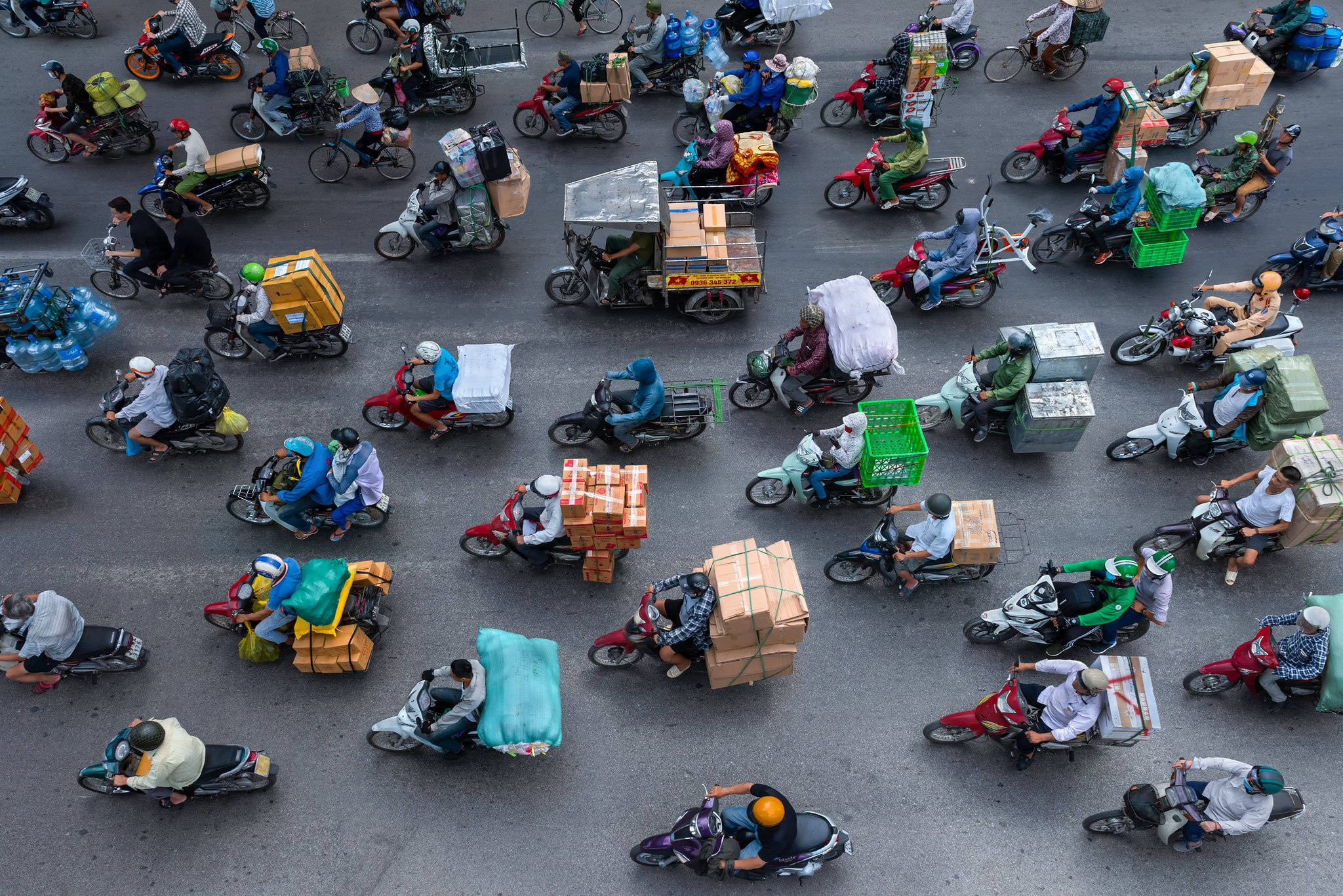 Vietnam 桌布 壁紙 — 繁忙城市街道的鳥瞰圖，街道上擠滿了騎著機車、載滿包裹和盒子的送貨員。
