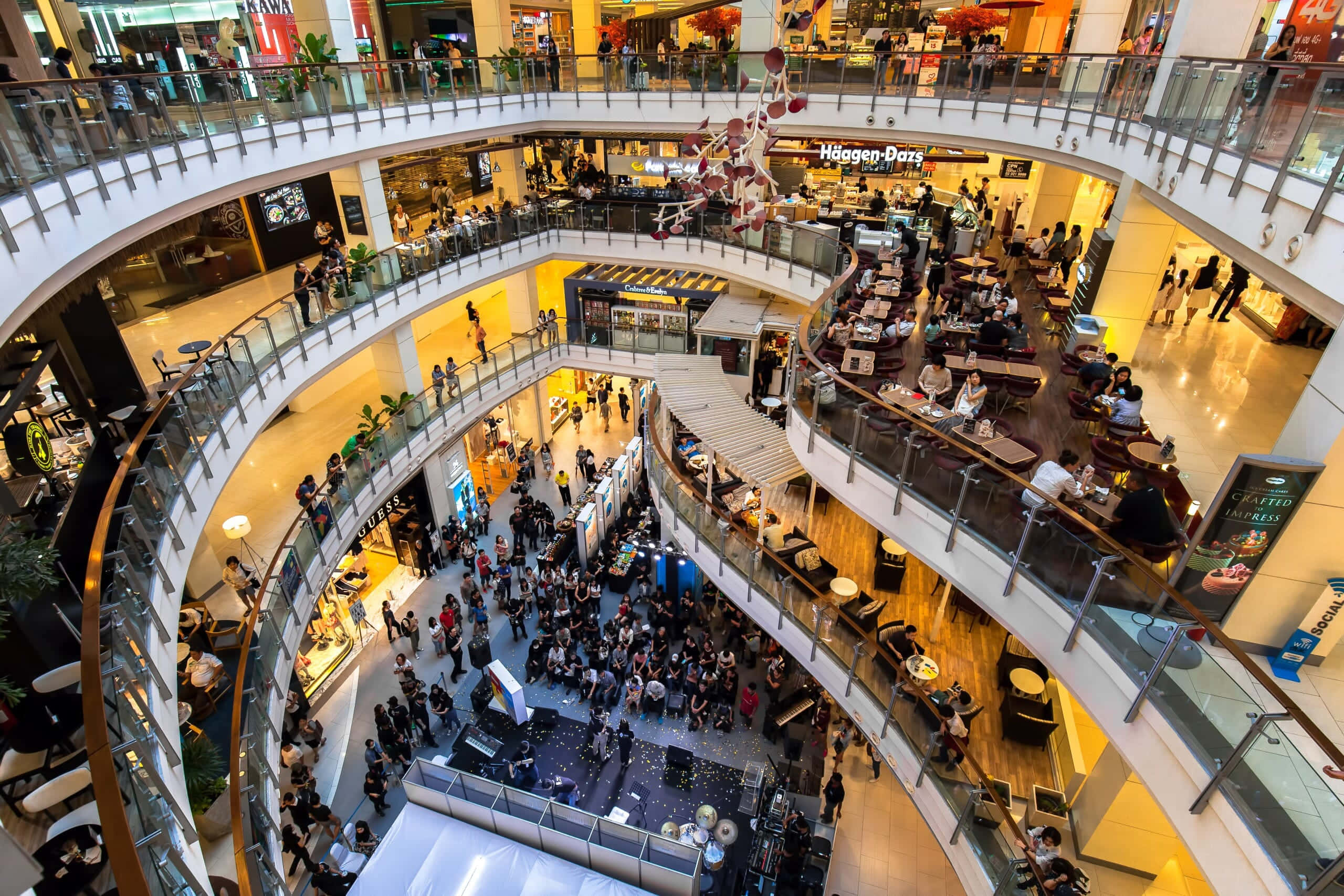 Mall 桌布 壁紙 — 繁忙多層購物中心的鳥瞰圖，人群穿過玻璃中庭和商店櫥窗。