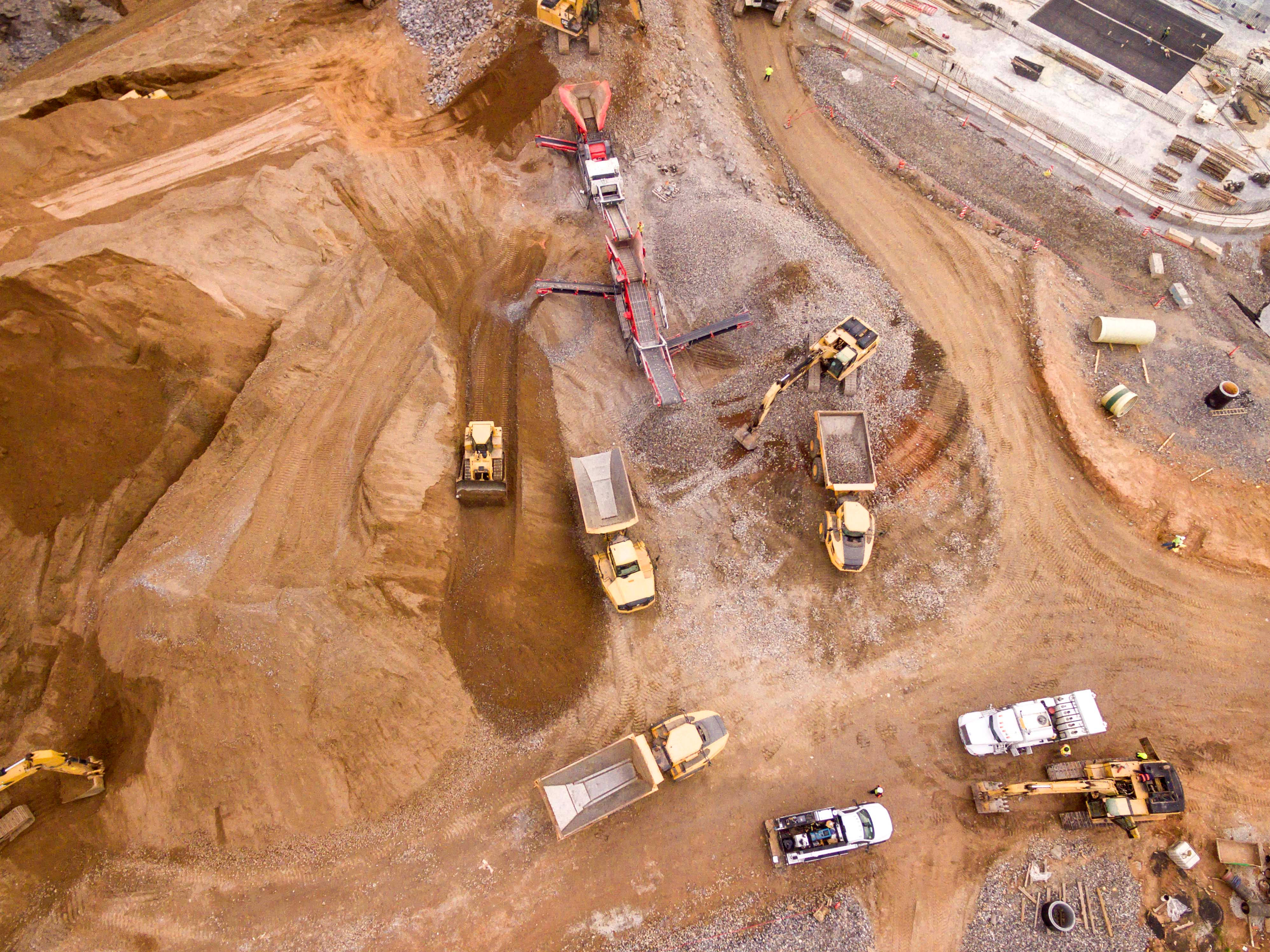 Mining 桌布 壁紙 — 繁忙建築工地的鳥瞰圖，重型機械在明亮的日光下移動泥土和礫石。