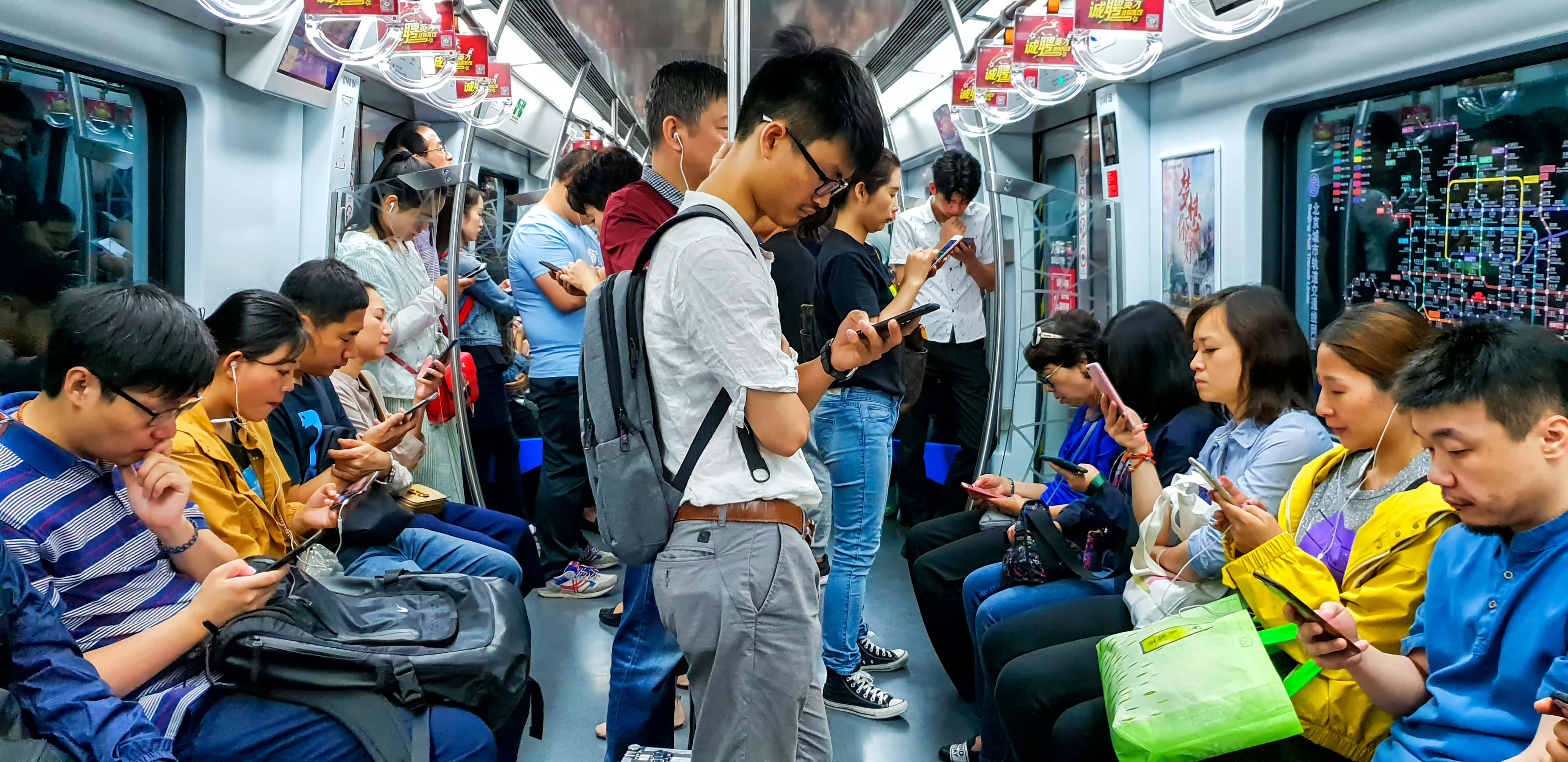 中國 桌布 壁紙 — 繁忙時間擠滿通勤者的地鐵車廂，所有人都全神貫注於智慧型手機。
