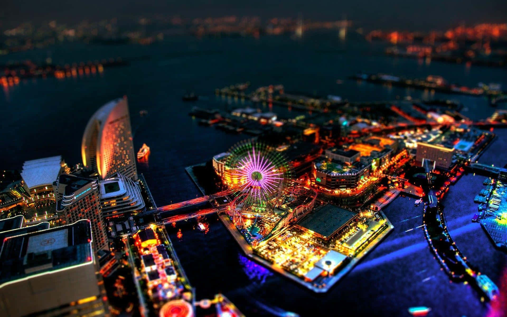 Impressive 桌布 壁紙 — 繁忙港口城市的充滿活力的夜間空中景觀，發光的燈光在水面上反射，還有一個色彩繽紛的摩天輪。