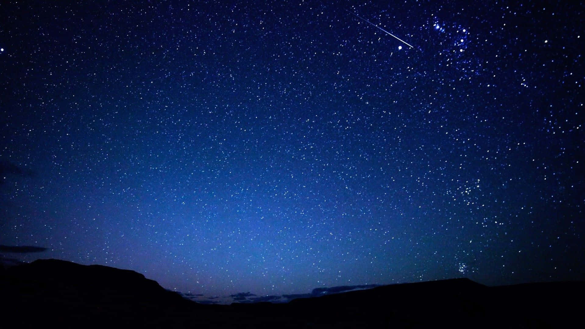 Chilly Night 桌布 壁紙 — 繁星點點的夜空，一顆明亮的流星劃過黑暗的山巒輪廓上方。
