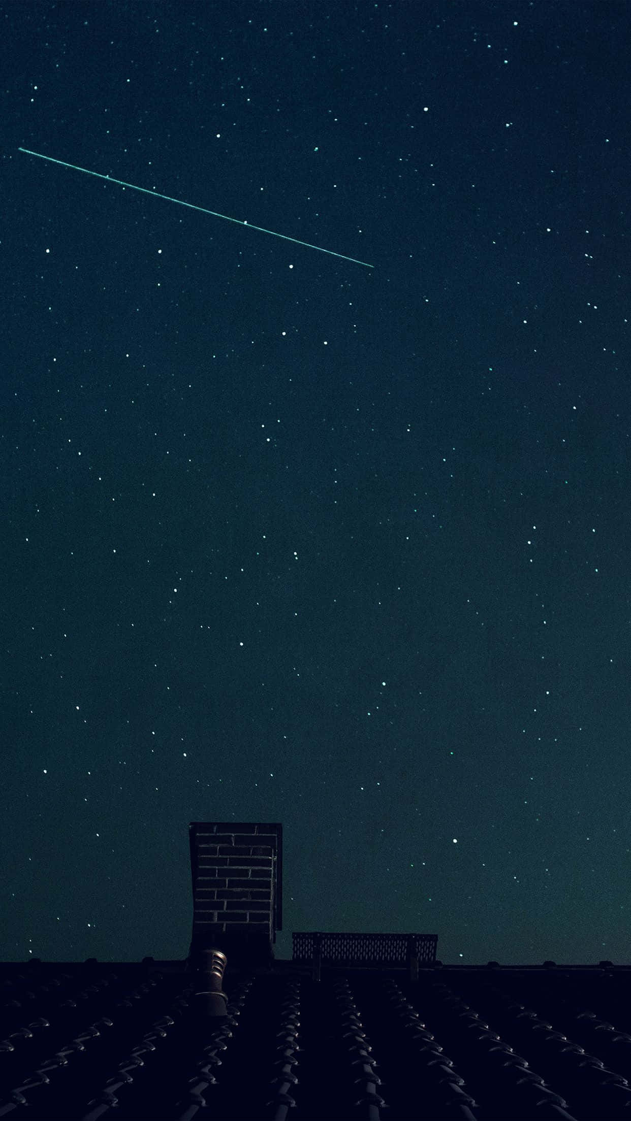 夜空 桌布 壁紙 — 繁星點點的夜空，一顆明亮的流星劃過黑暗的屋頂和煙囪上方。