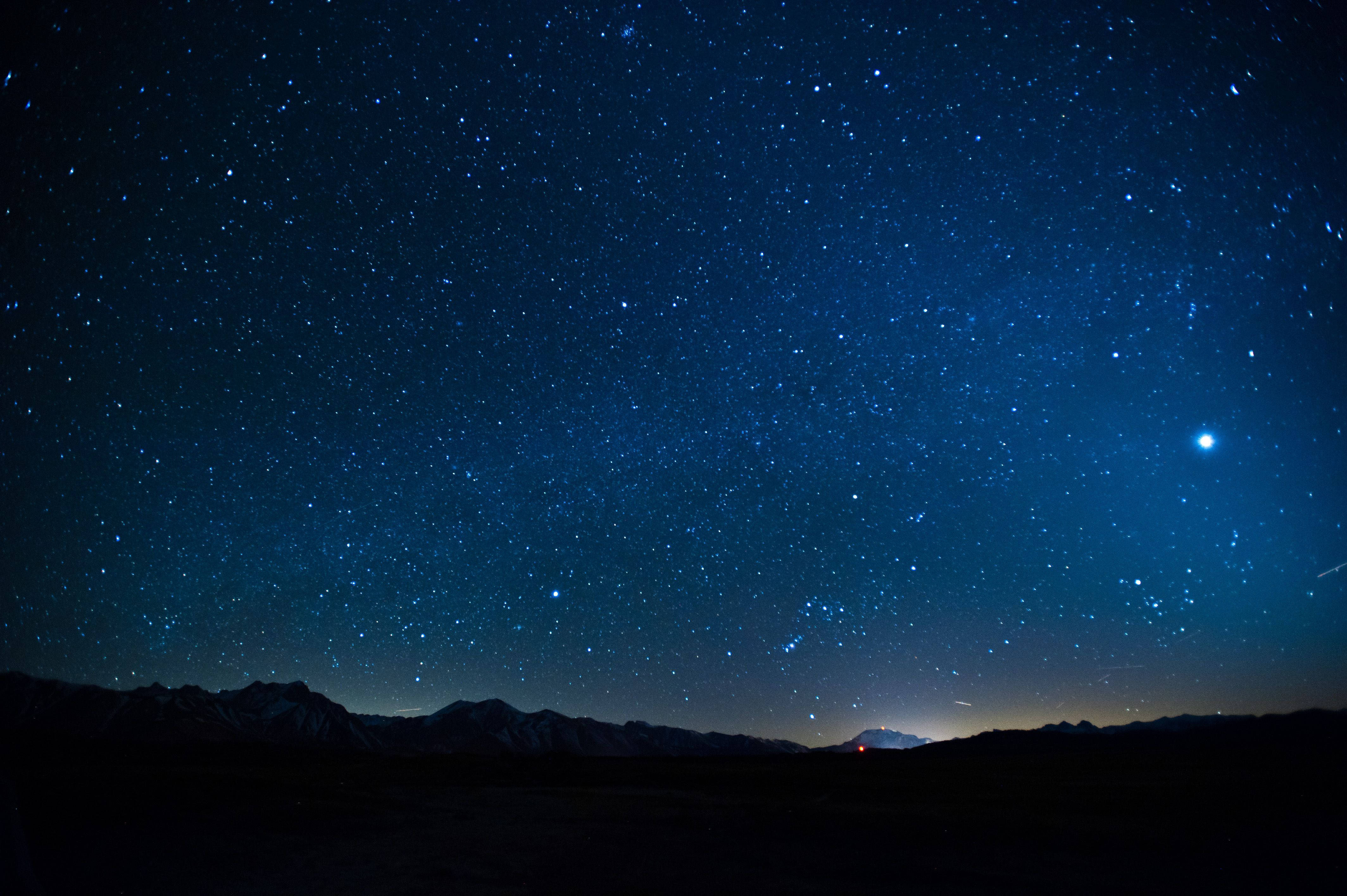 Stars 桌布 壁紙 — 繁星點點的夜空，一顆明亮的行星和淡淡的銀河拱起在黑暗的山巒剪影之上。