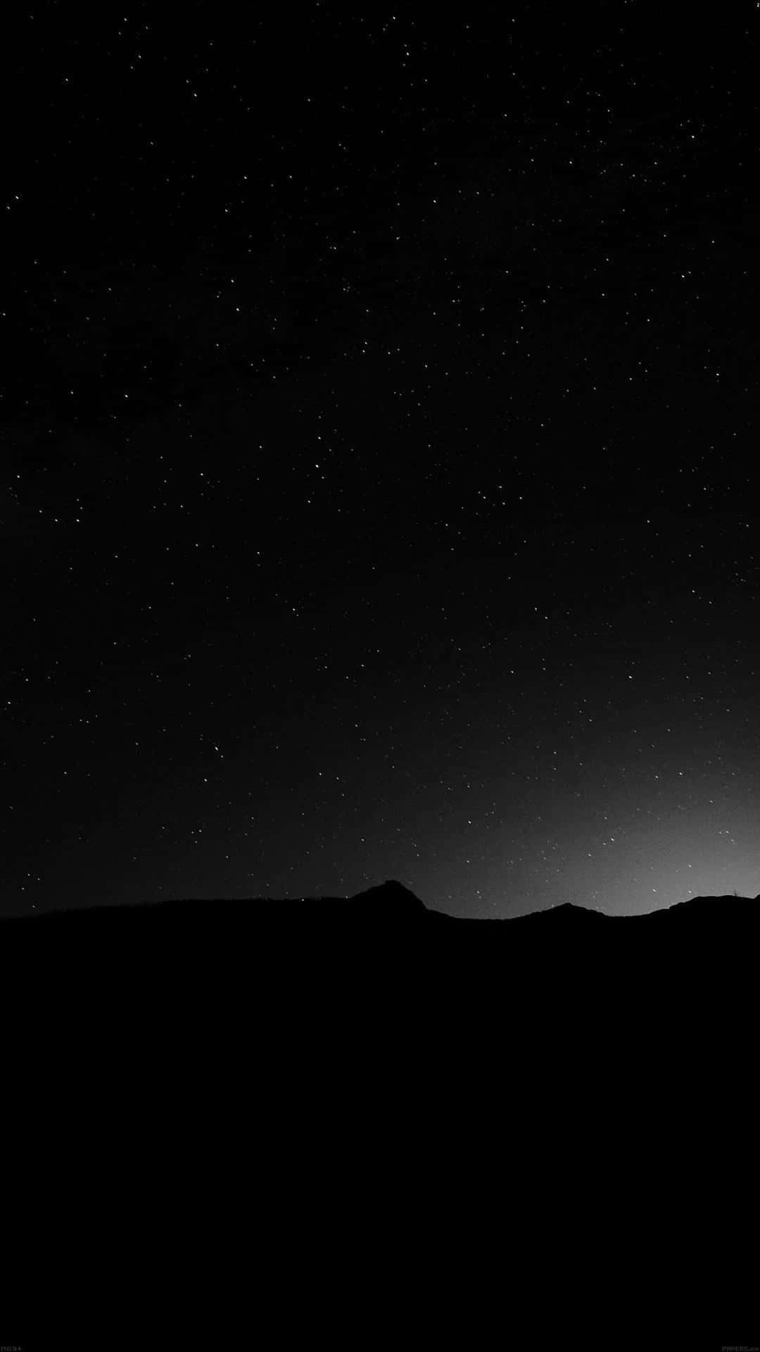 photography iPhone 桌布 壁紙 — 繁星點點的夜空，地平線上有微弱的光芒，上方是黑暗的山脈輪廓。