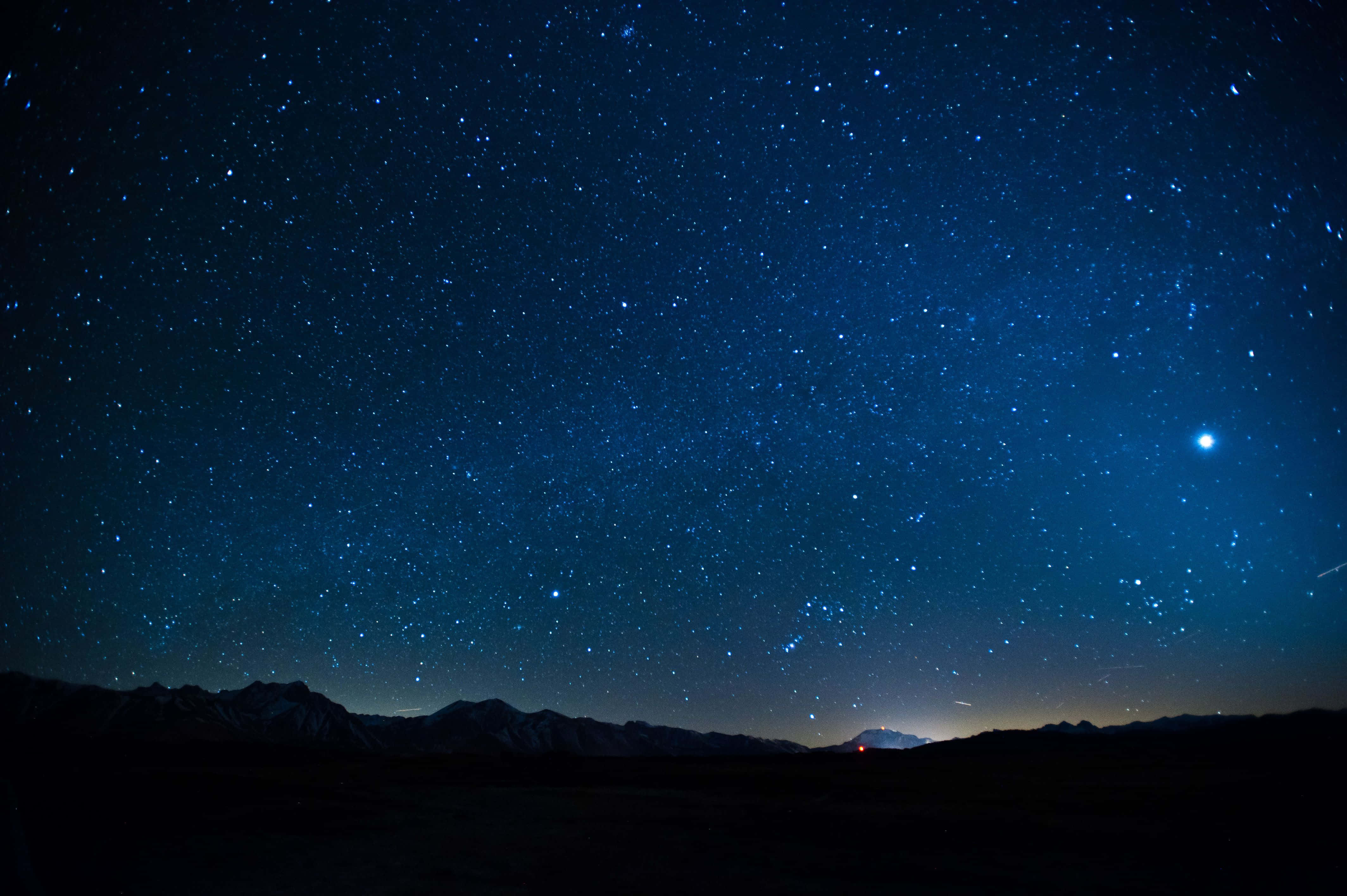 Stars 桌布 壁紙 — 繁星點點的夜空，明亮的行星和微弱的流星軌跡在黑暗的山脈輪廓之上。