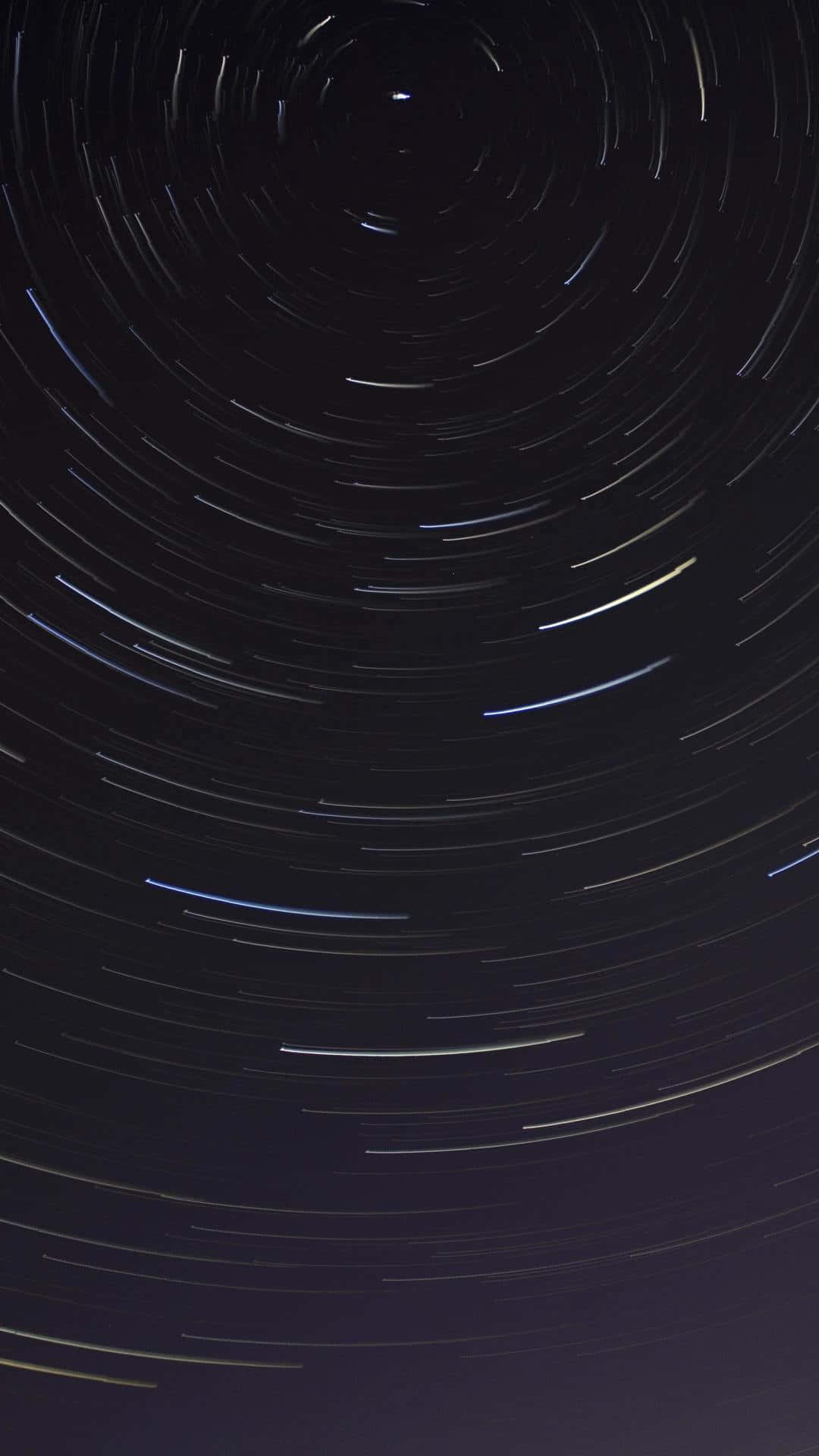 time lapse 桌布 壁紙 — 繁星點點的夜空，星星圍繞中心點旋轉，形成旋轉的光跡。
