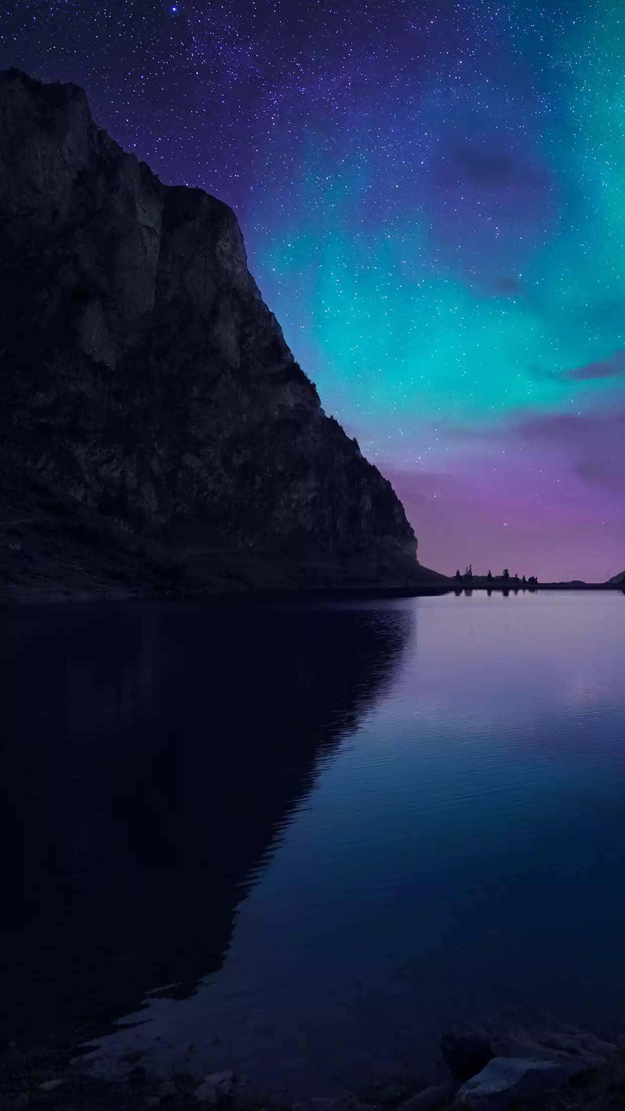 山景 桌布 壁紙 — 繁星點點的夜空，絢麗的北極光照耀在平靜的湖面上，旁邊是黑暗的岩石峭壁。