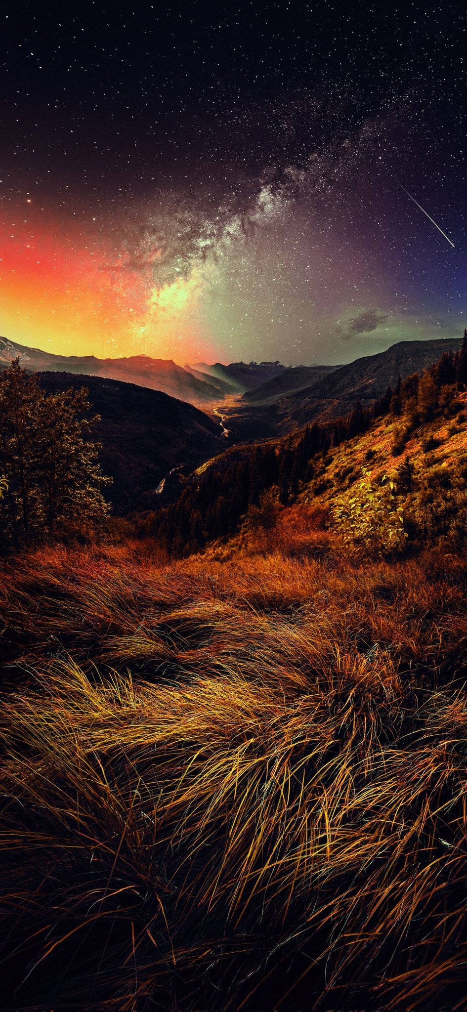 4K 桌布 壁紙 — 繁星點點的夜空，銀河在一個山谷上方彎曲，地平線上有發光的橙色和紫色色調。