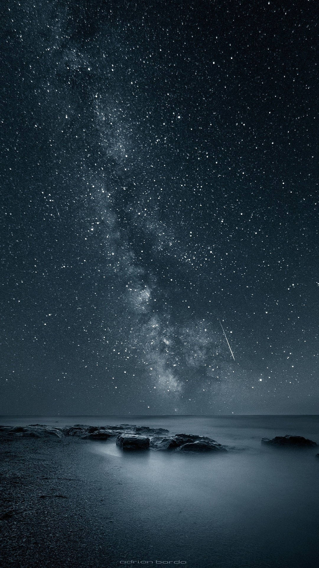 Starry Sky 桌布 壁紙 — 繁星點點的夜空，銀河在平靜的海洋和黑暗的岩石上拱起。