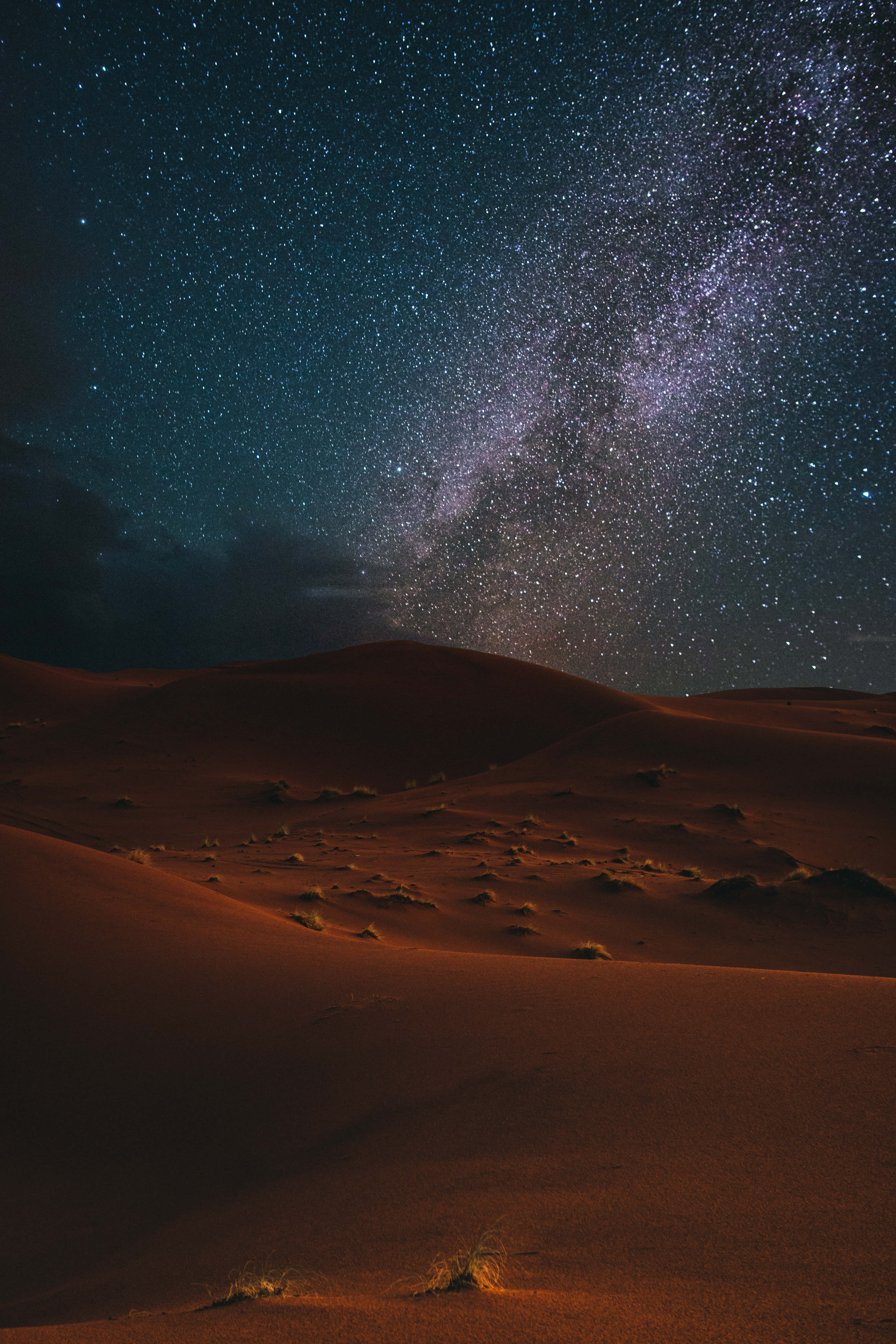 沙漠 桌布 壁紙 — 繁星點點的夜空，銀河在深藍色廣闊天空下拱形掠過發光的橙色沙漠沙丘。