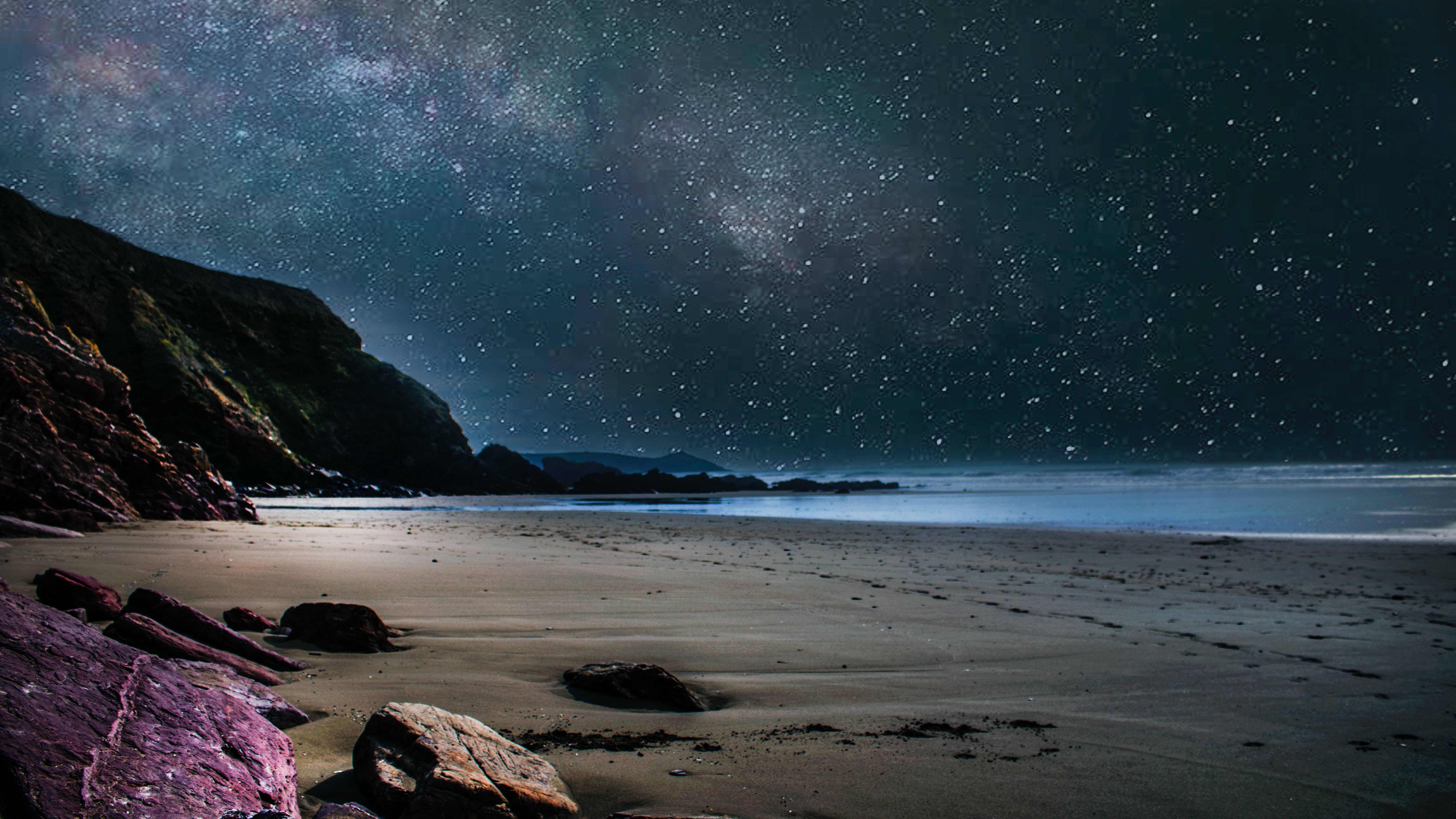 桌布 壁紙 — 繁星點點的夜空，銀河拱起在寧靜的海灘上，有黑暗的懸崖和發光的紫色岩石。
