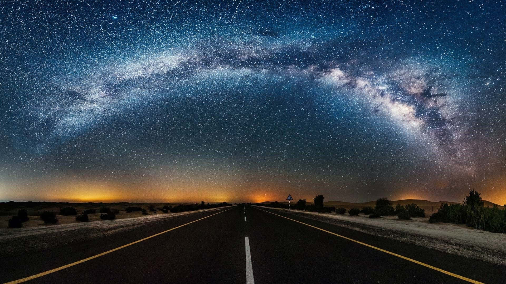 highway 桌布 壁紙 — 繁星點點的夜空，銀河拱跨在一條筆直延伸至地平線的沙漠公路上。