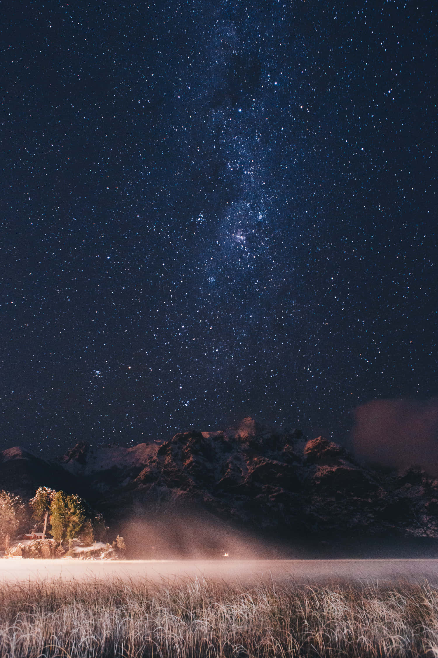 Night Time 桌布 壁紙 — 繁星點點的夜空，銀河拱跨雪覆山巒與霧氣瀰漫的冰凍湖泊。