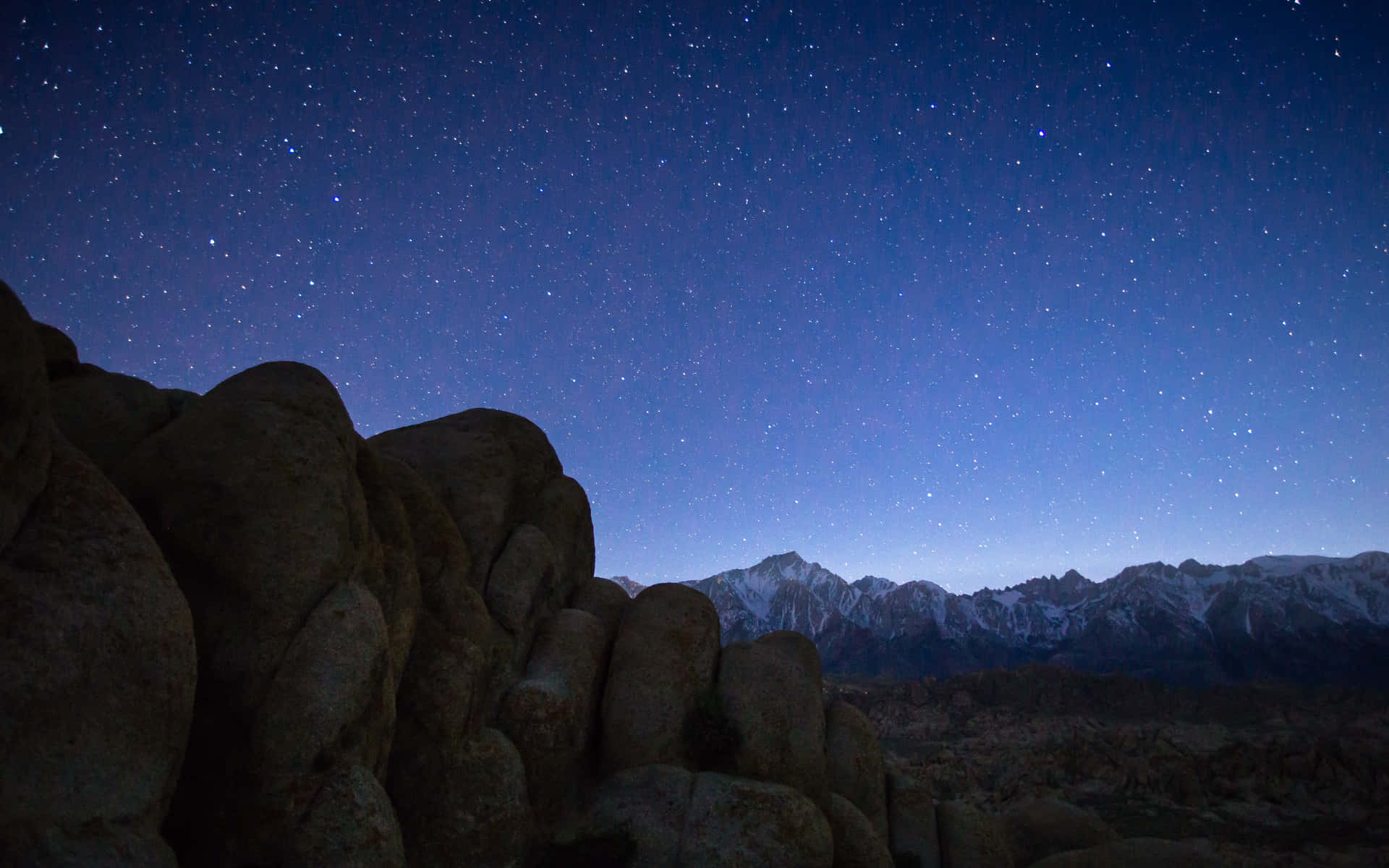 Rocks 桌布 壁紙 — 繁星點點的夜空在沙漠景觀中閃耀在積雪覆蓋的山脈和崎嶇的巨石之上。