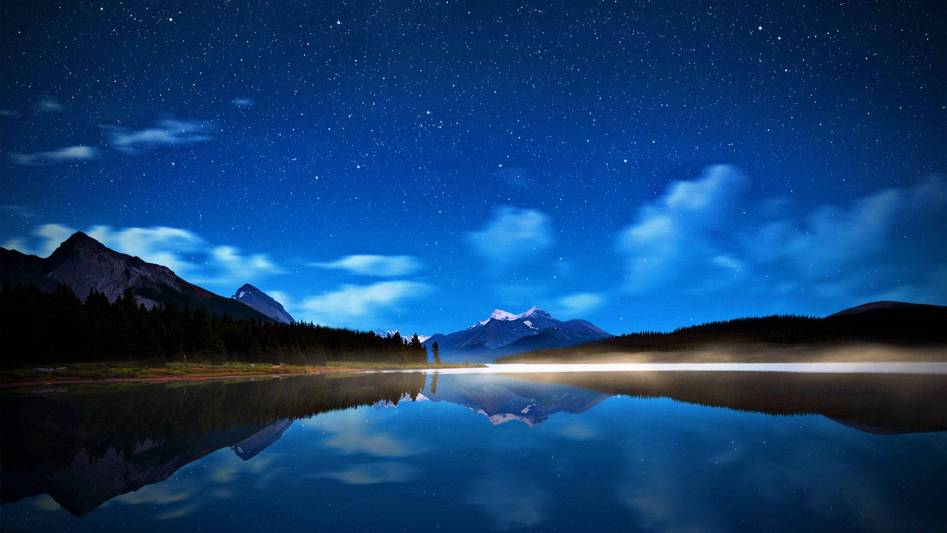 夜空 桌布 壁紙 — 繁星點點的夜空完美地倒映在平靜的湖面上，四周環繞著黑暗的山脈和樹木。