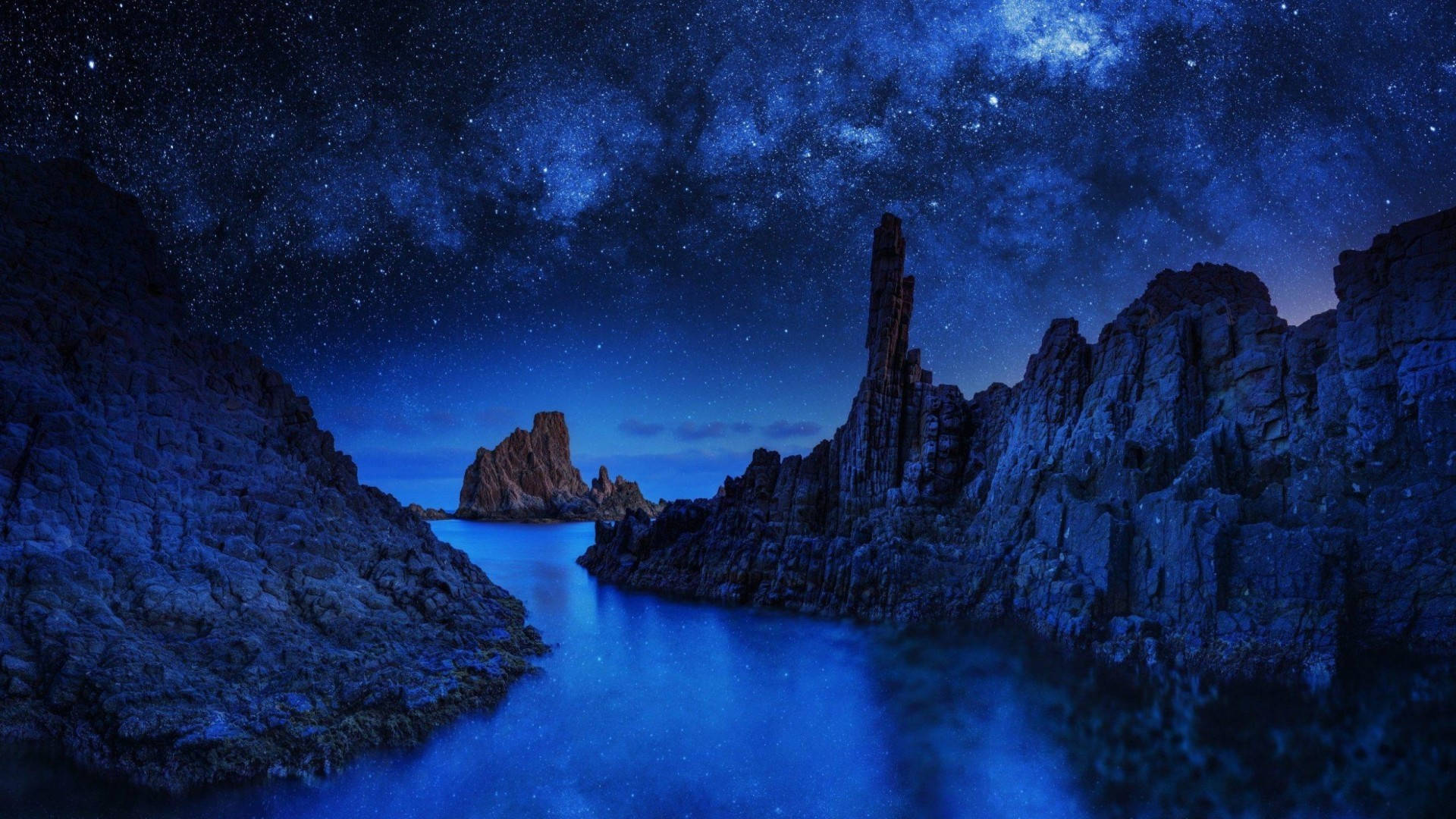 安卓 桌布 壁紙 — 繁星點點的夜空拱形籠罩在一條寧靜的藍色水道之上，兩側是崎嶇的岩石地貌。