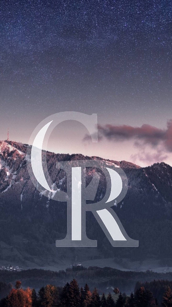 Rockies 桌布 壁紙 — 繁星點點的夜空拱形籠罩著積雪的山脈，一個巨大的半透明字母組合覆蓋在山峰和森林之上。