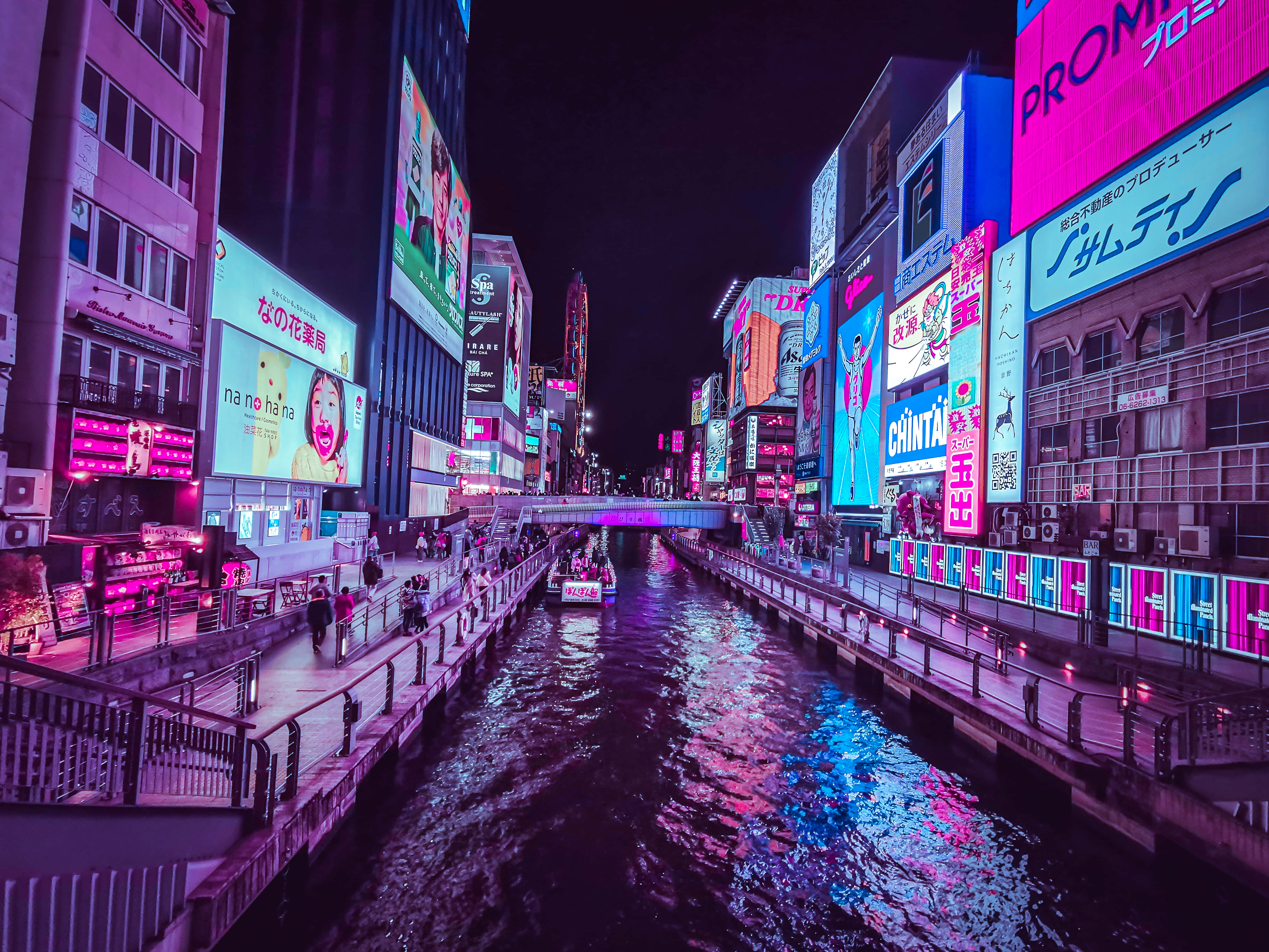 Neon Aesthetic Phone 桌布 壁紙 — 繁華日本城市夜晚中一條霓虹燈照亮的運河，發光的廣告牌倒映在水面上。