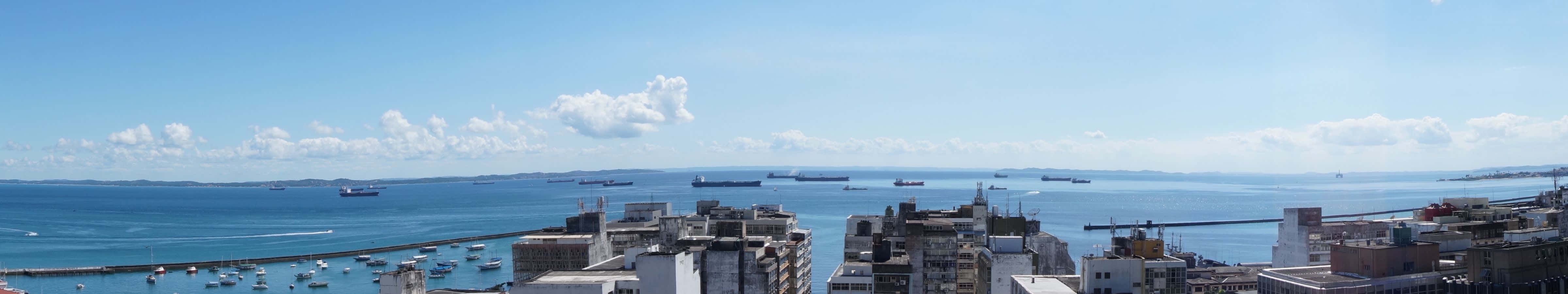 4800x900 桌布 壁紙 — 繁華海岸城市的全景，擁有現代建築、停滿船隻的港口，以及海洋上方清澈的藍天。