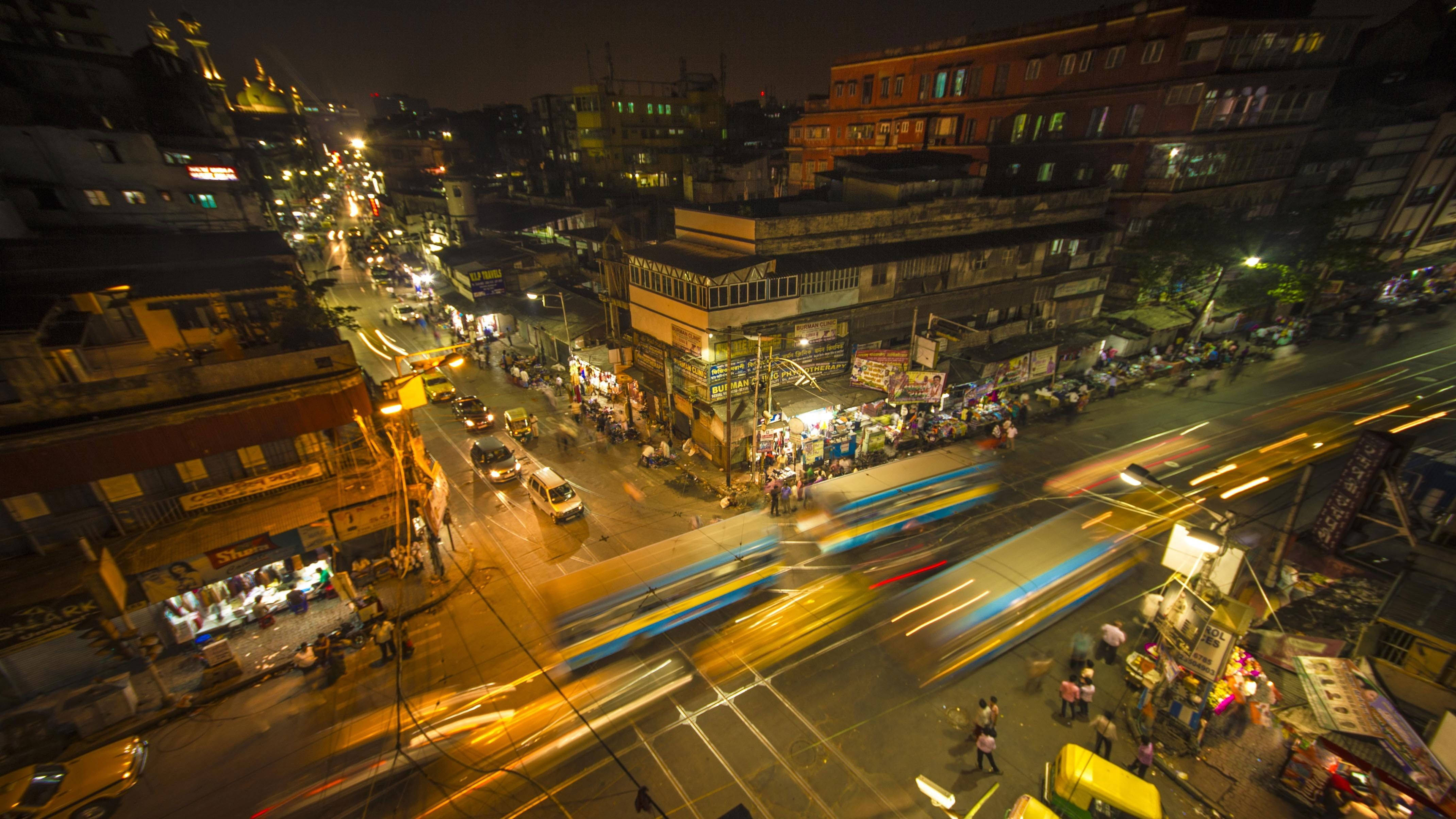 Kolkata 桌布 壁紙 — 繁華的夜間城市街道，充滿發光的燈光和移動車輛的條紋。