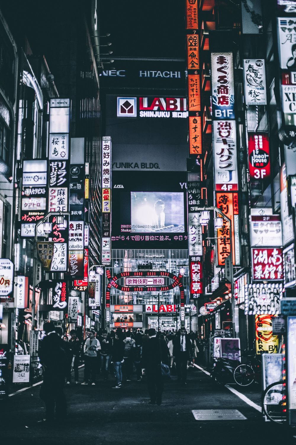 桌布 壁紙 — 繁華的東京夜晚街道，霓虹燈閃爍，高聳的招牌和下方的人群。
