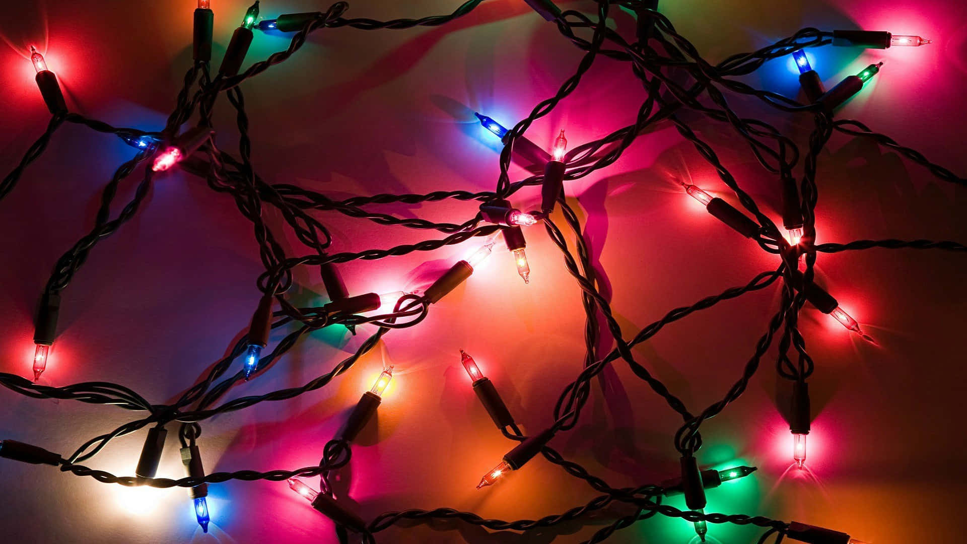 lights 桌布 壁紙 — 纏繞的彩色聖誕燈串在柔和的漸變背景上溫暖地發光。