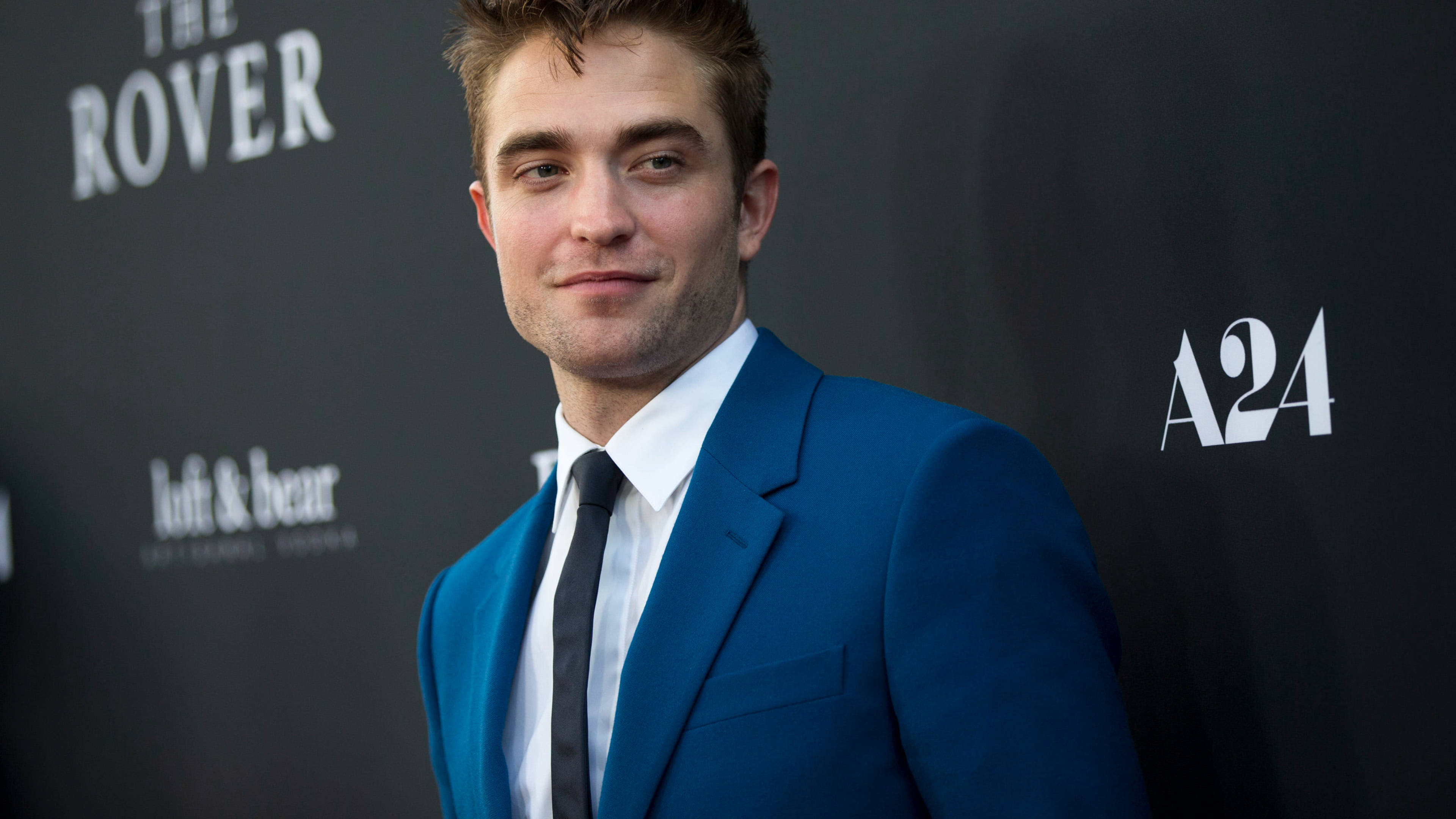Robert Pattinson 桌布 壁紙 — 羅伯·派汀森在電影首映會上穿著俐落的藍色西裝自信微笑。