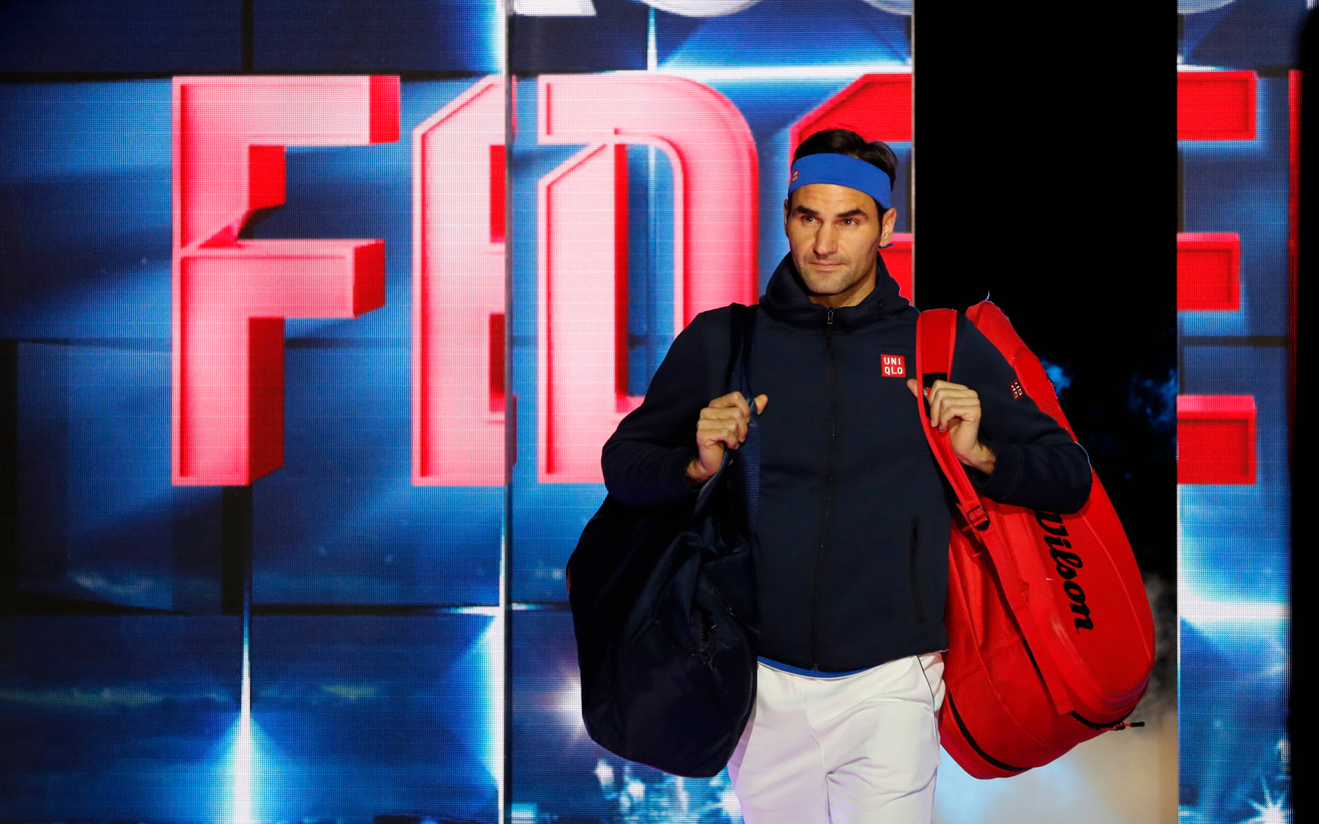 roger 桌布 壁紙 — 羅傑·費德勒自信地拿著網球袋，走在發光的紅色「FEDERER」背景前。