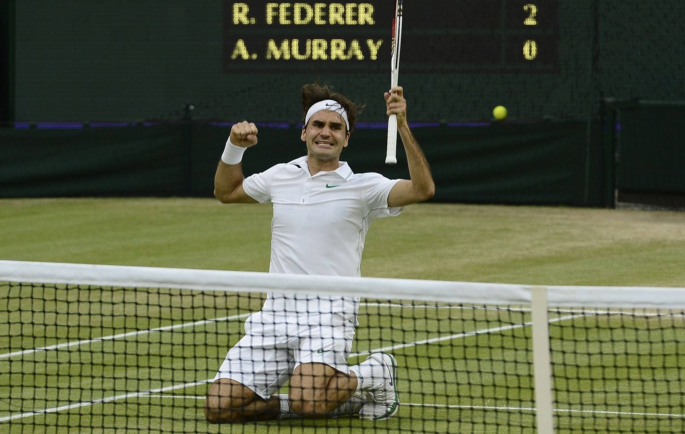 Wimbledon 桌布 壁紙 — 羅傑·費德勒跪在草地場上，在記分板下高舉球拍並握拳慶祝勝利。