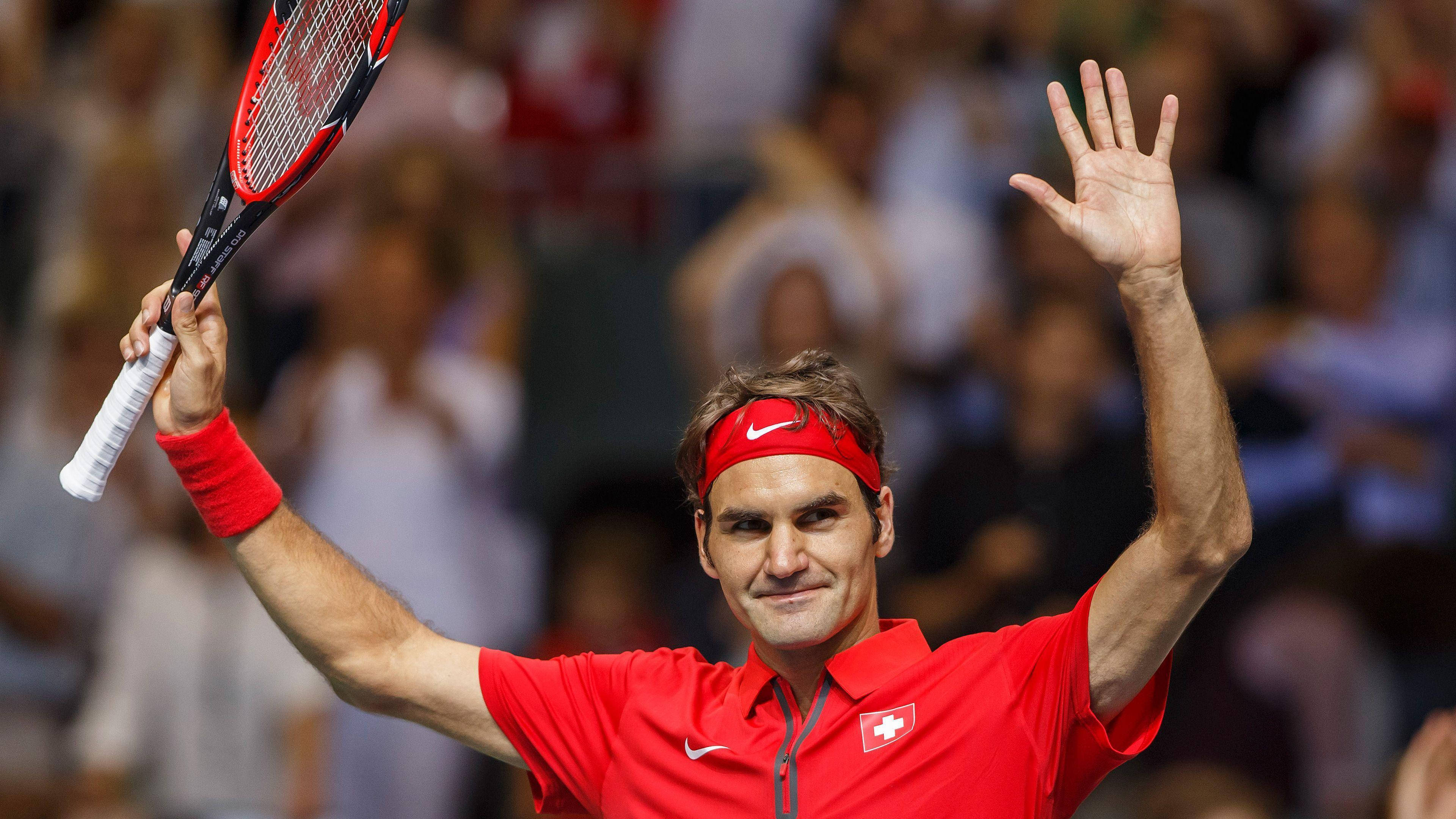 roger 桌布 壁紙 — 羅傑·費德勒身穿紅色襯衫和頭帶，高舉網球拍以勝利姿勢向人群揮手。
