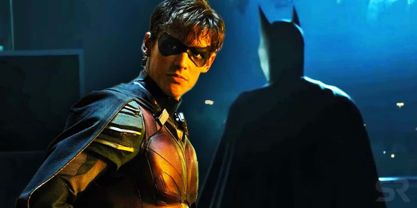 Batman Vs Robin 桌布 壁紙 — 羅賓站在戲劇性的藍光中，面對蝙蝠俠的剪影，營造出緊張的電影時刻。
